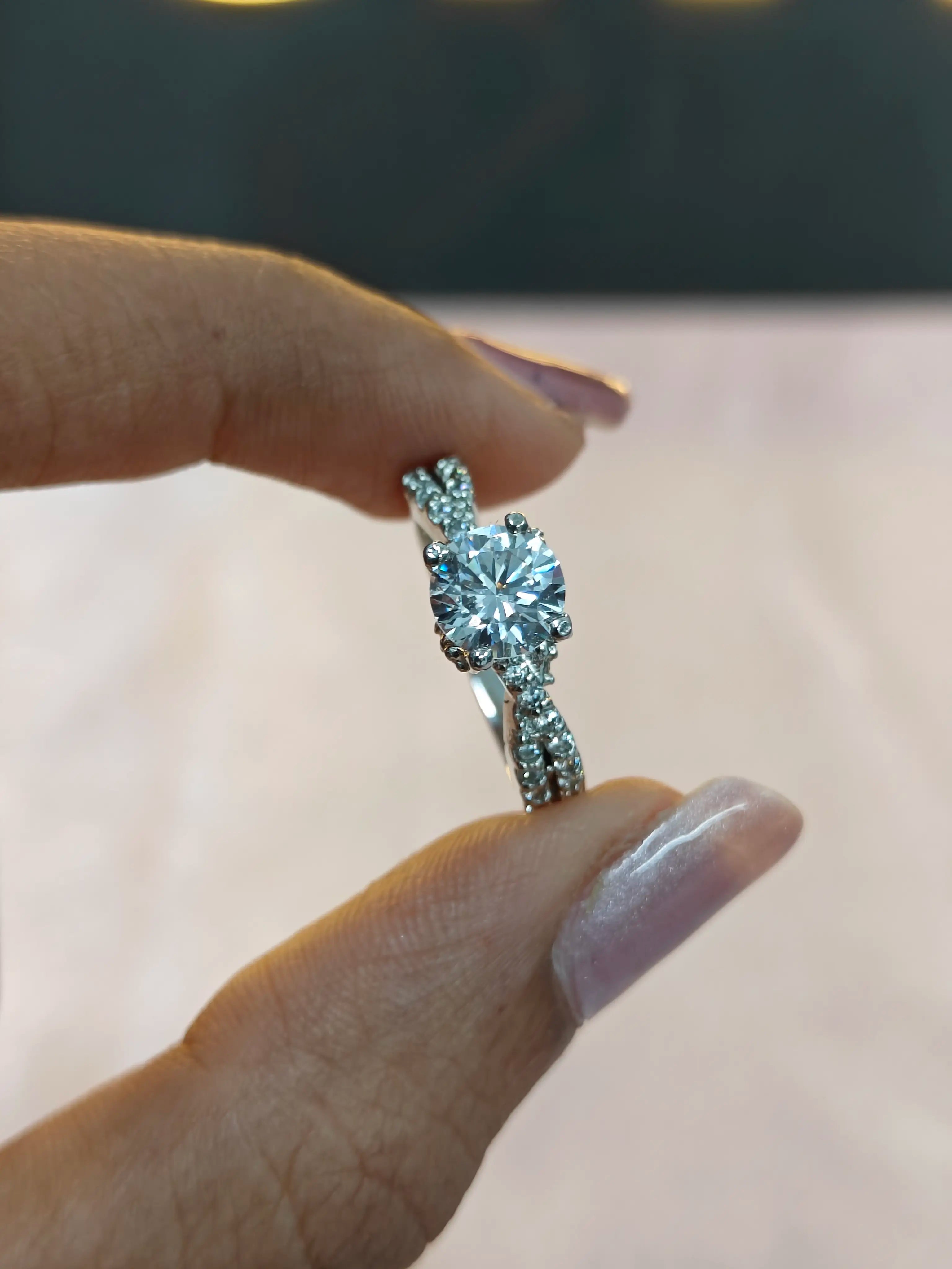 Diamond ring held between fingers against a neutral background