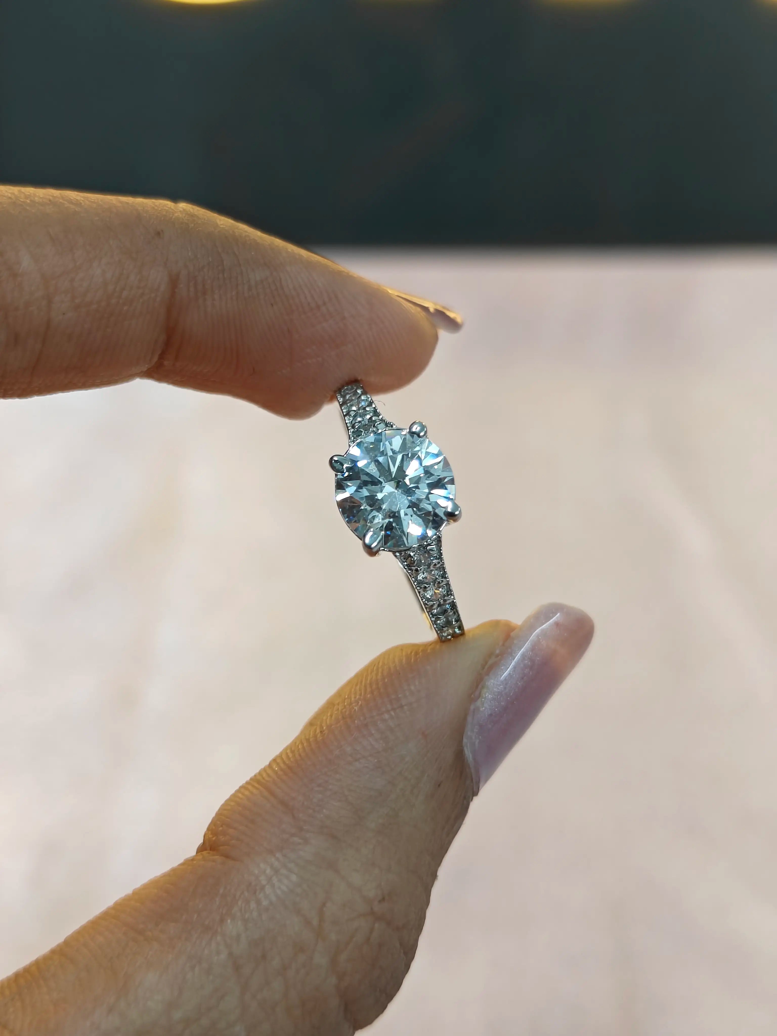 Diamond ring held between fingers against a neutral background