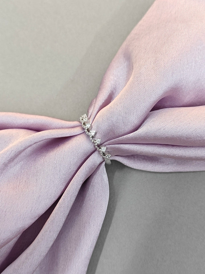 Close-up of a pink fabric bow with a decorative brooch on a light gray background
