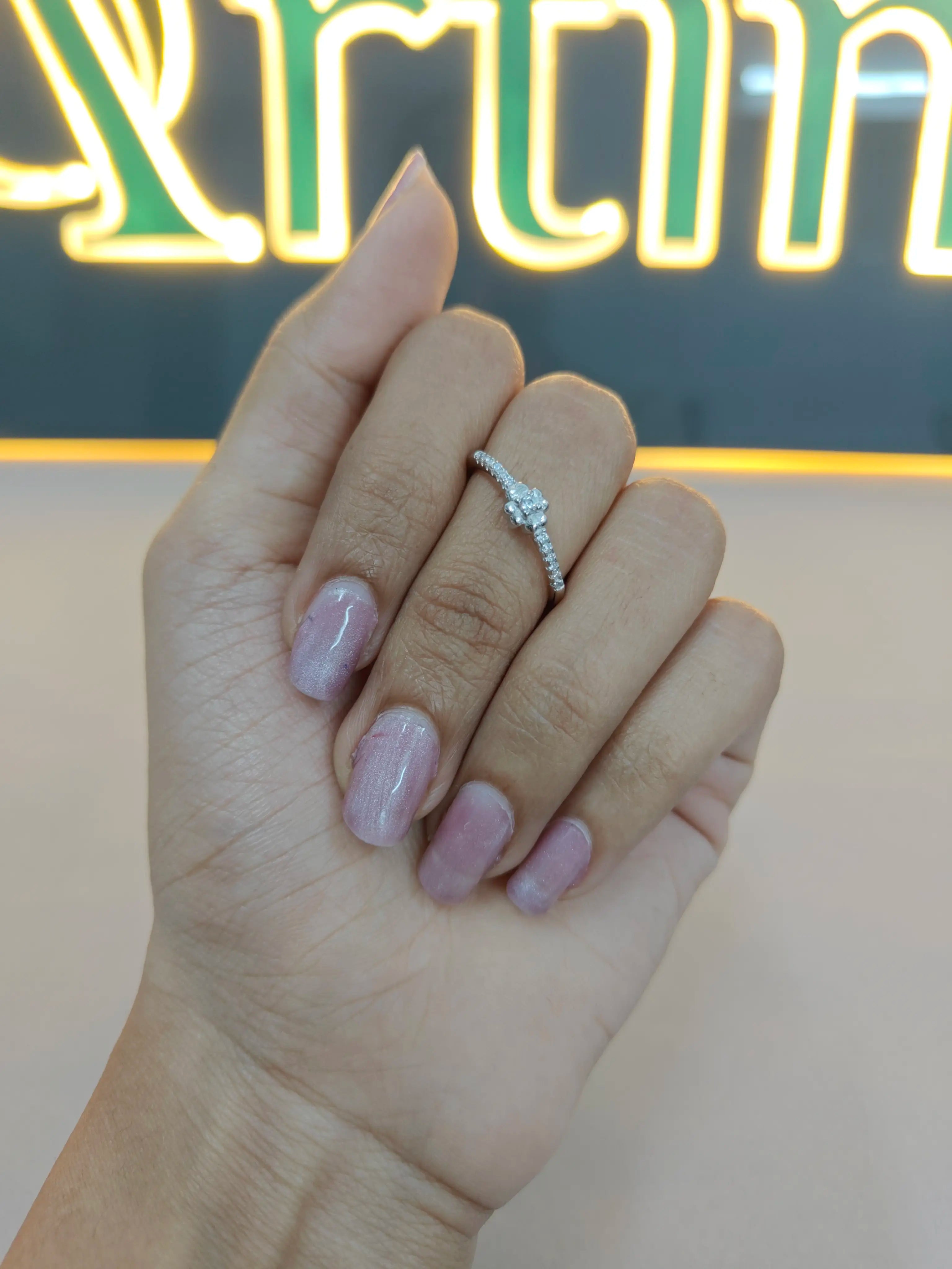 Hand wearing a diamond ring with a blurred background