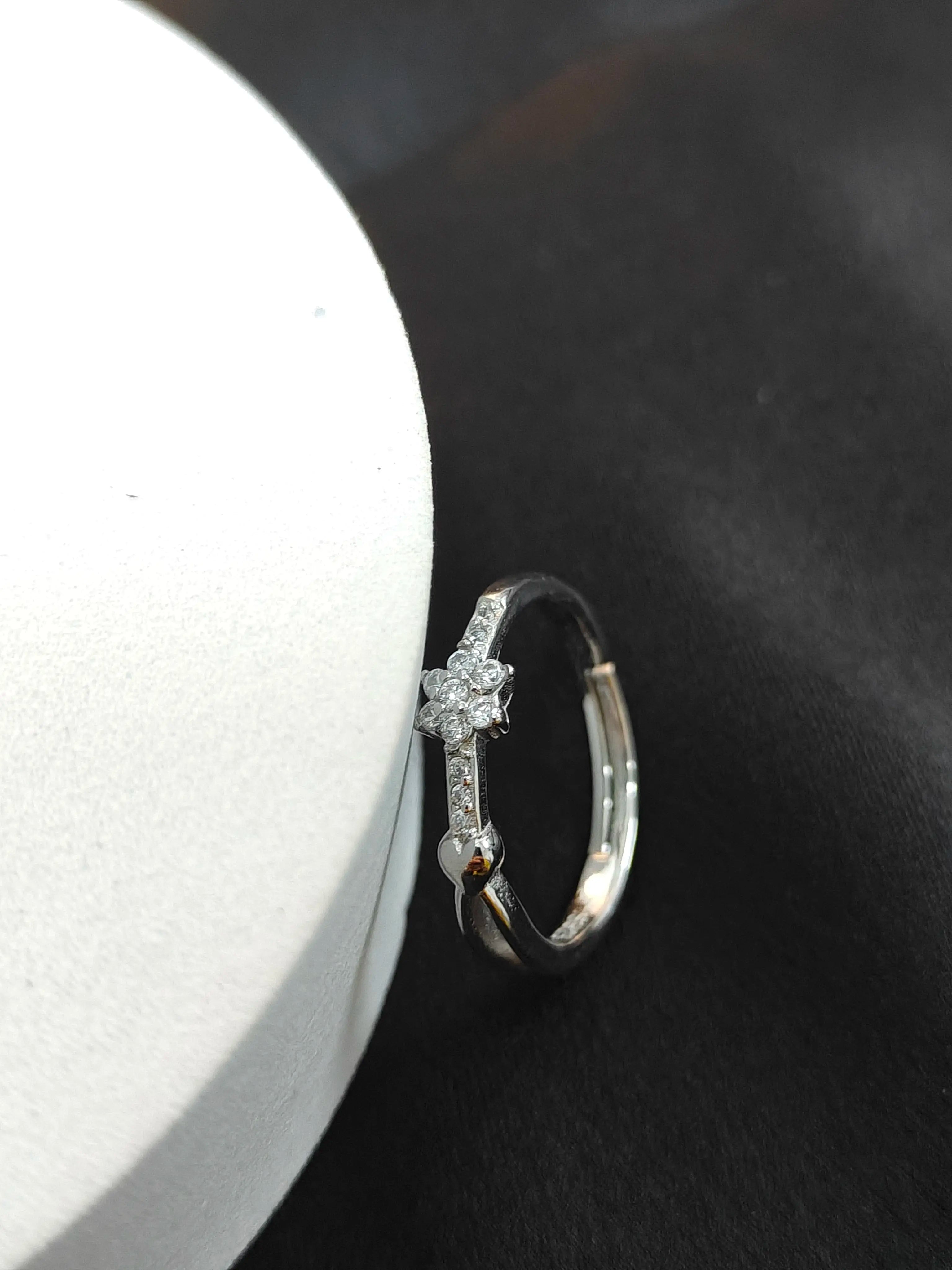 Silver ring with diamond accents on a dark surface