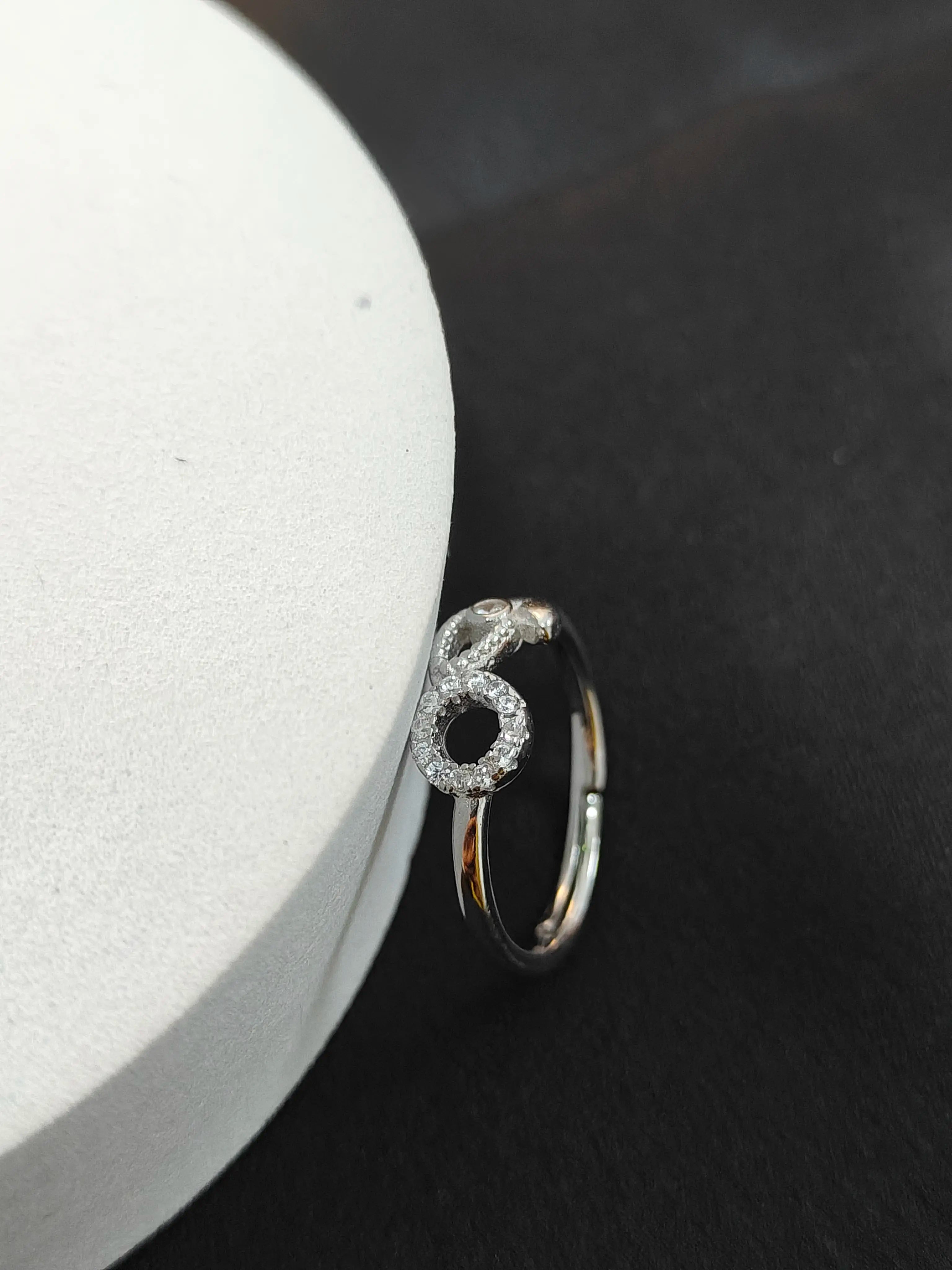 Silver ring with a number '6' design on a black and white background