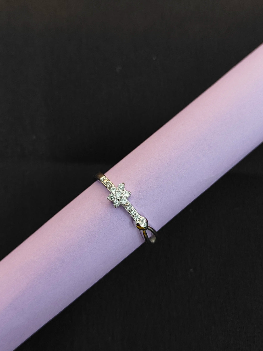 Gold ring with green gemstones on a pink surface against a black background