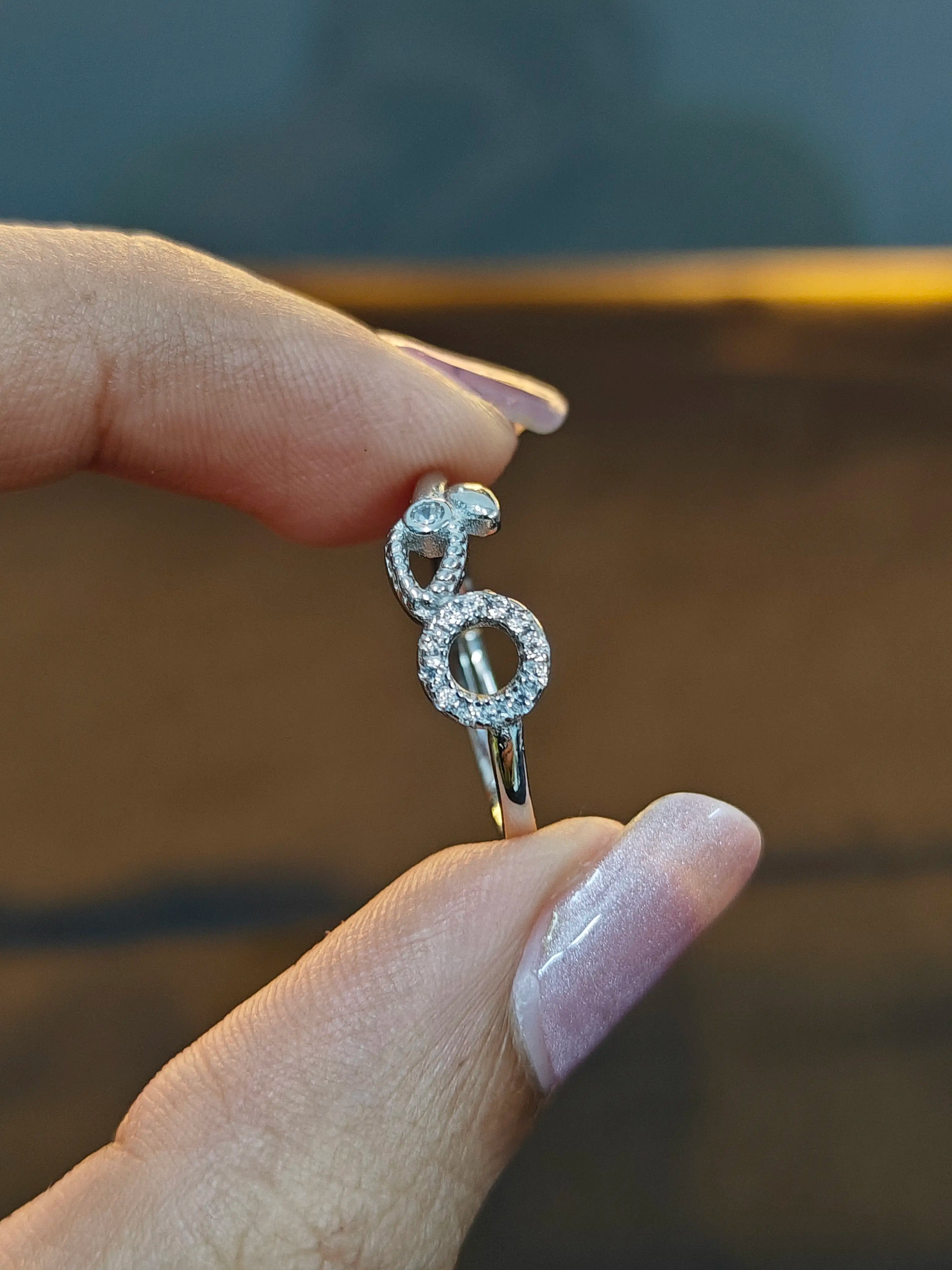 Silver ring with a unique design held by a hand against a blurred background