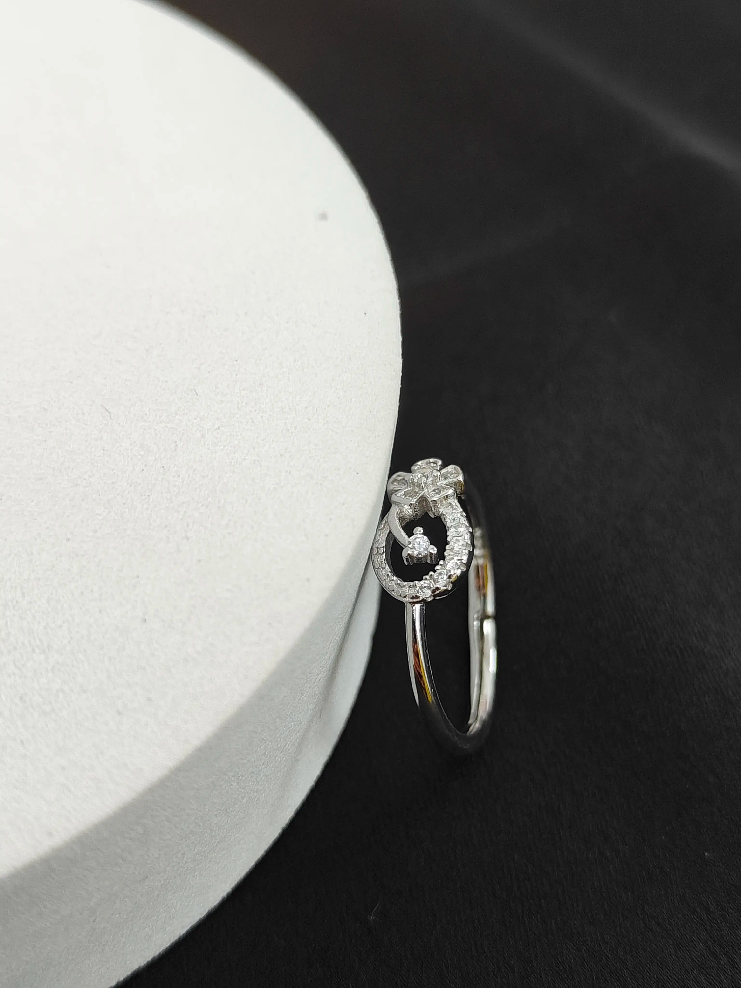 Silver ring with a decorative design on a dark surface