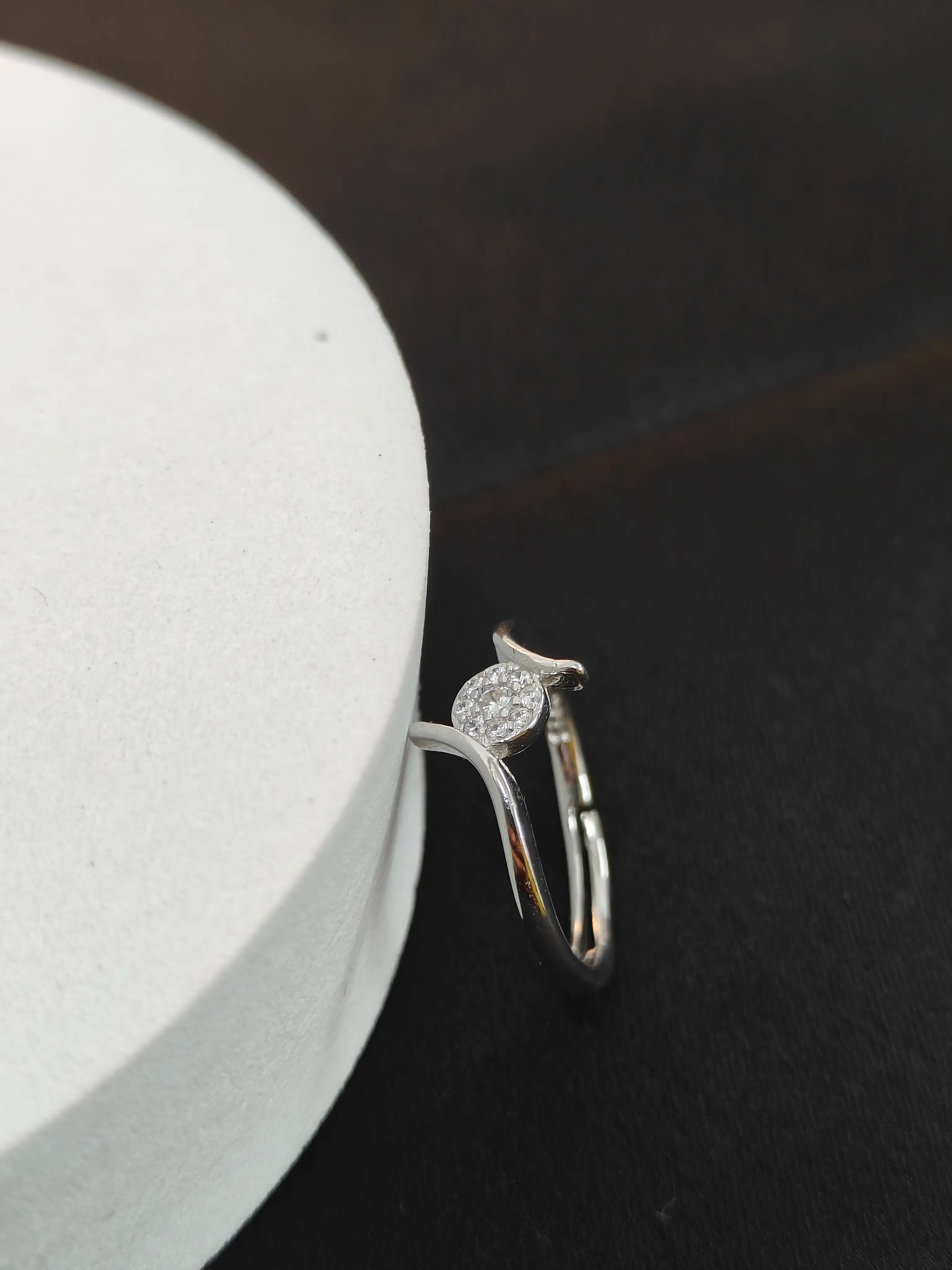 Silver ring with a small diamond on a dark surface