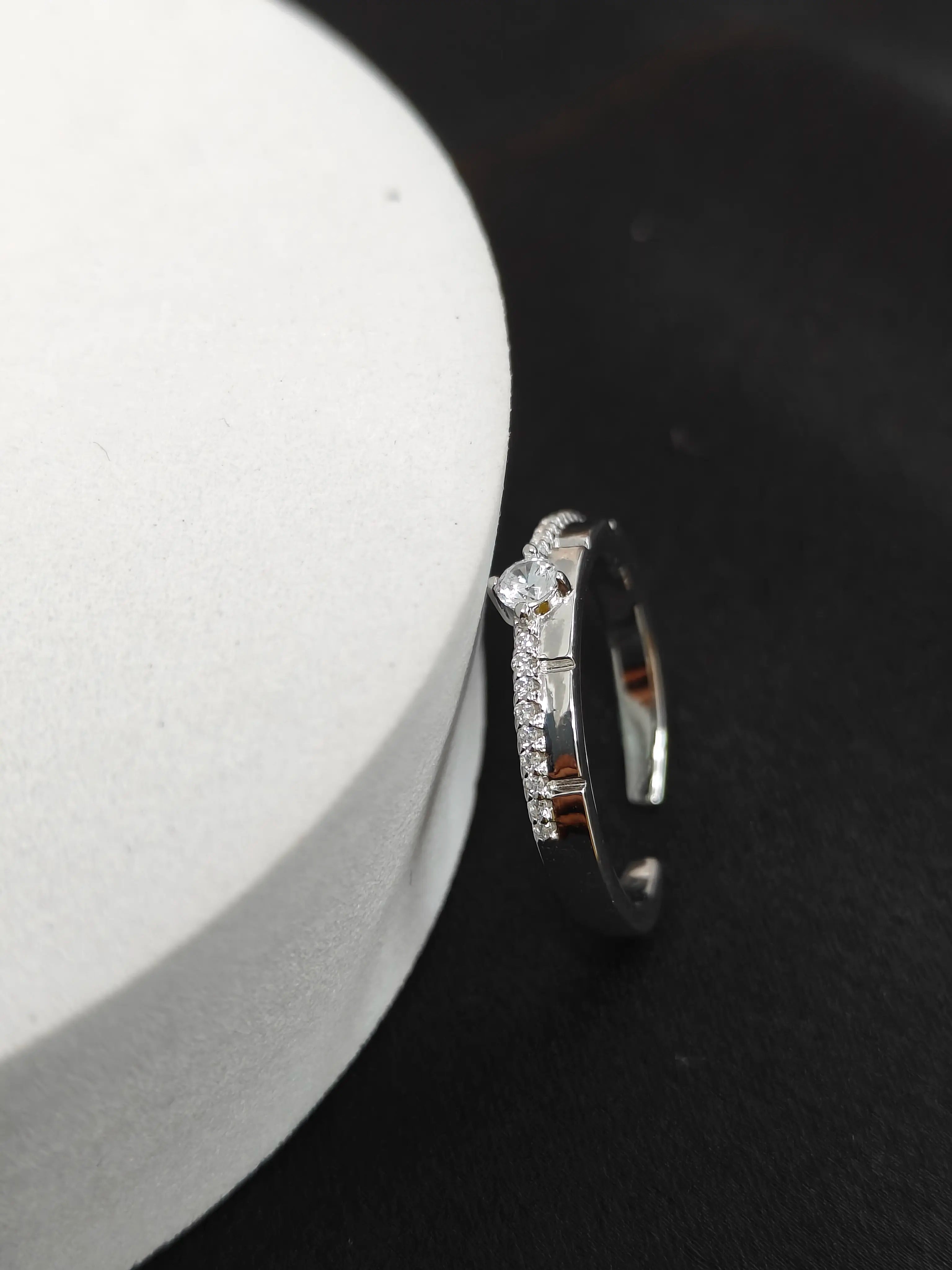 Silver hoop earring with small diamonds on a black background