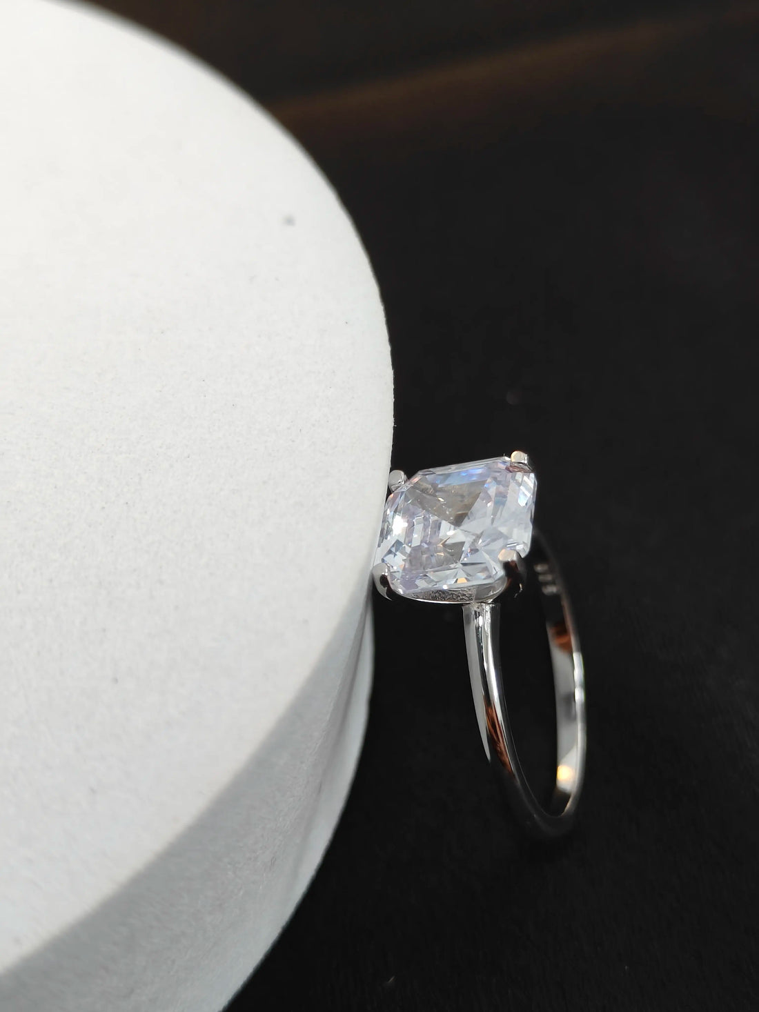 Silver ring with a large diamond on a dark surface