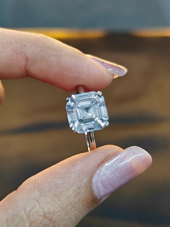 Diamond ring held between fingers against a blurred background