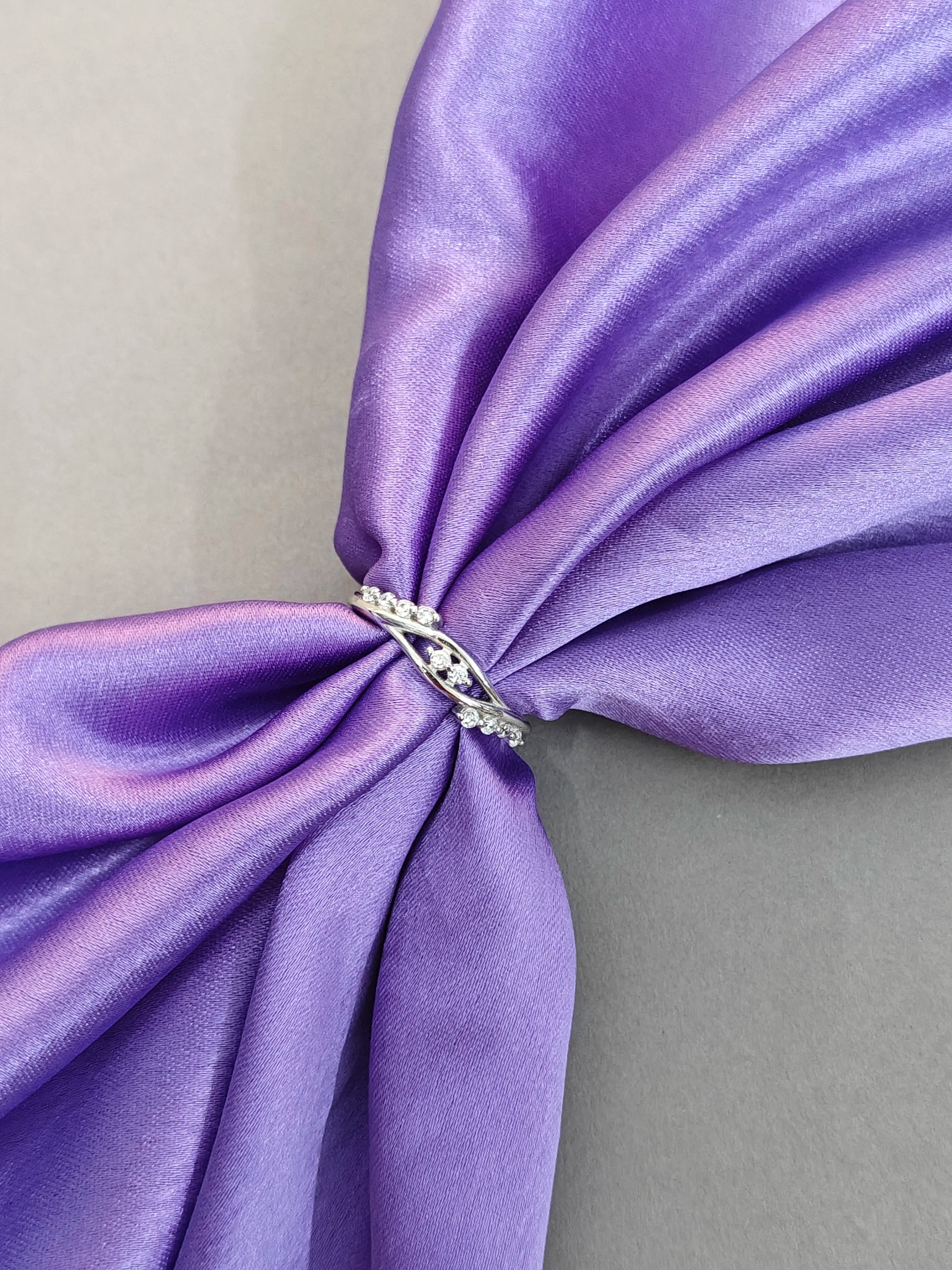 Close-up of a silver ring with a diamond on a purple fabric background