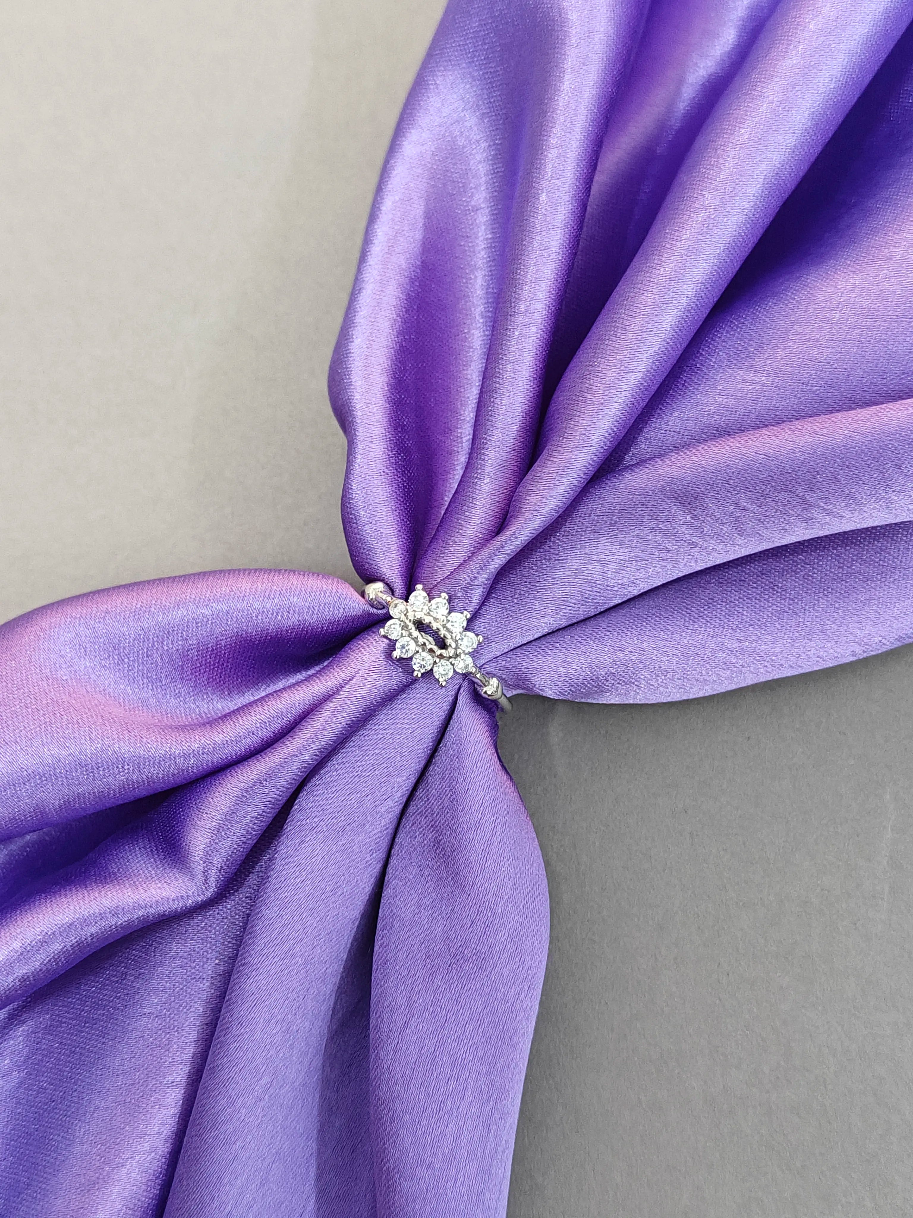 Purple fabric with a decorative brooch on a neutral background