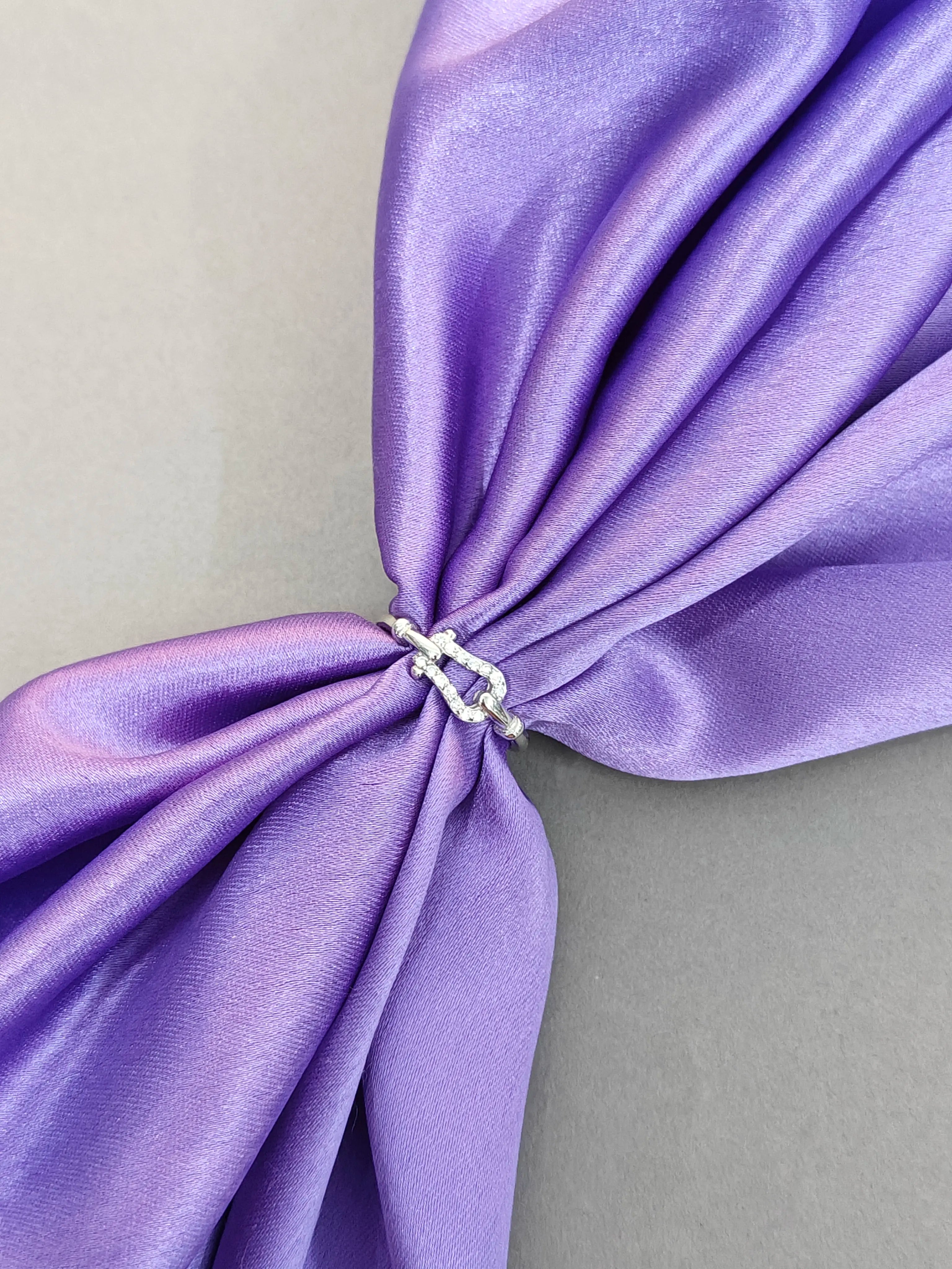 Close-up of a purple fabric bow with a metal clip on a gray background