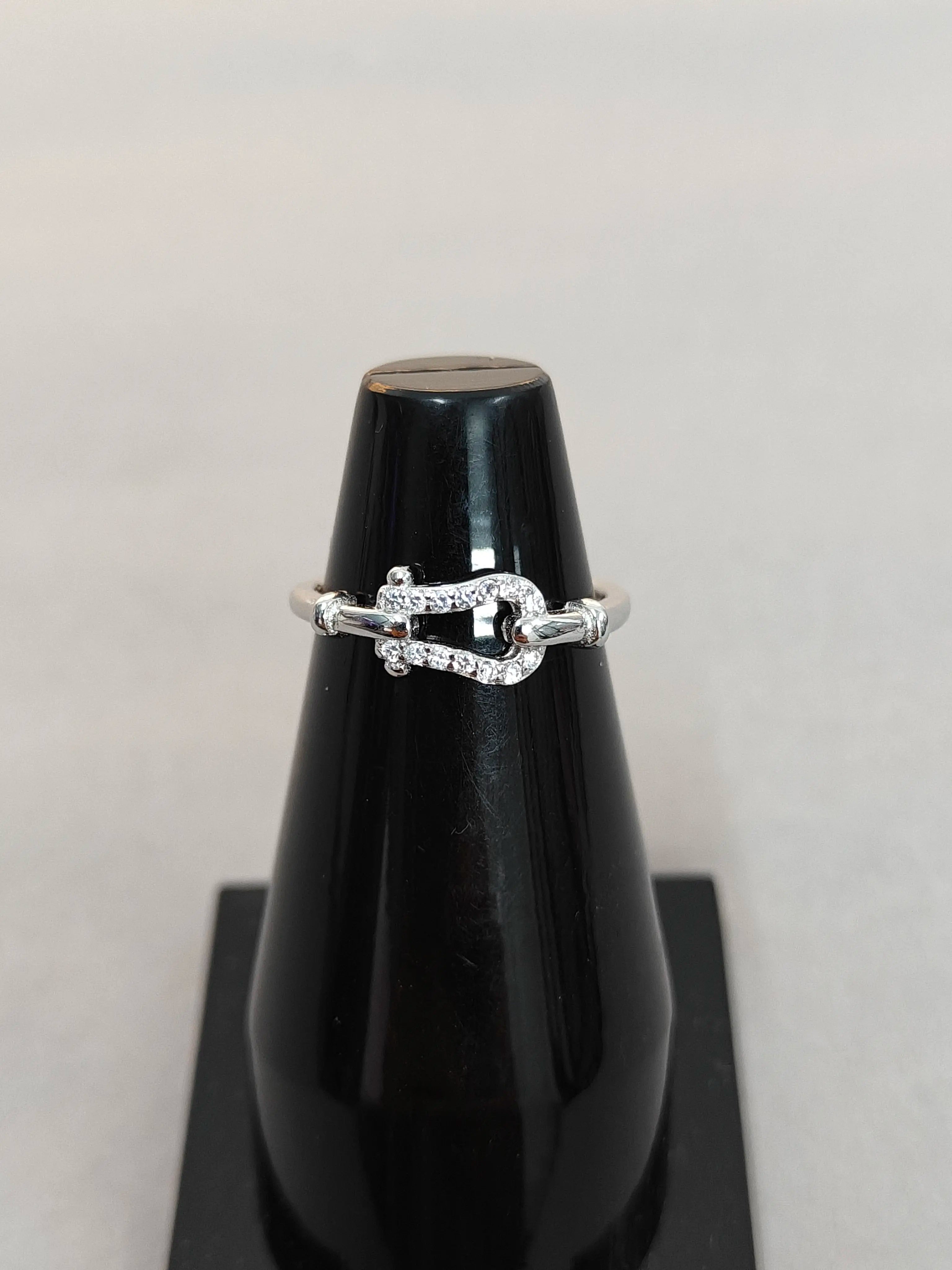 Silver ring with small diamonds on a black stand against a light gray background