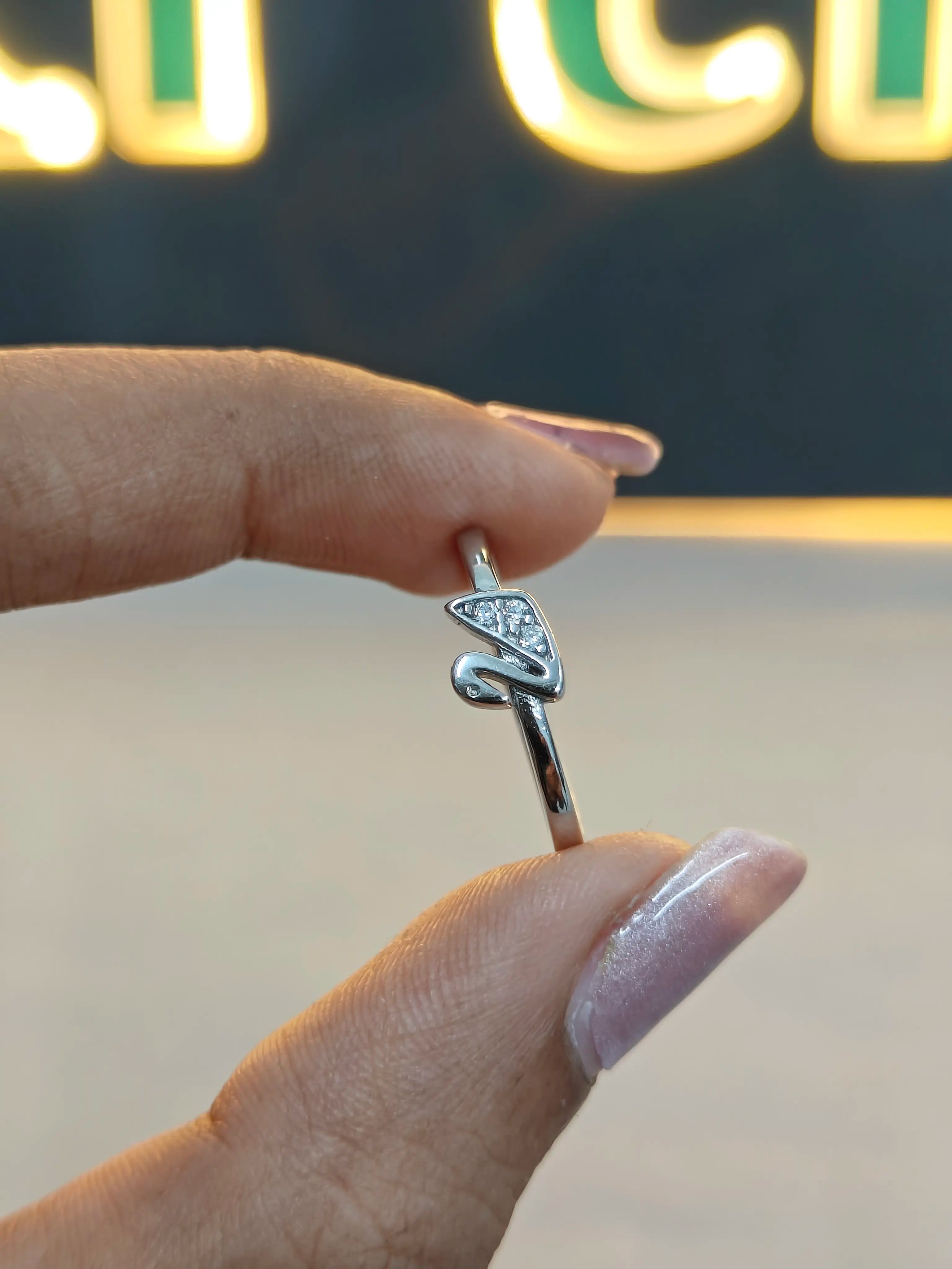 Silver ring with a diamond on a finger against a blurred background