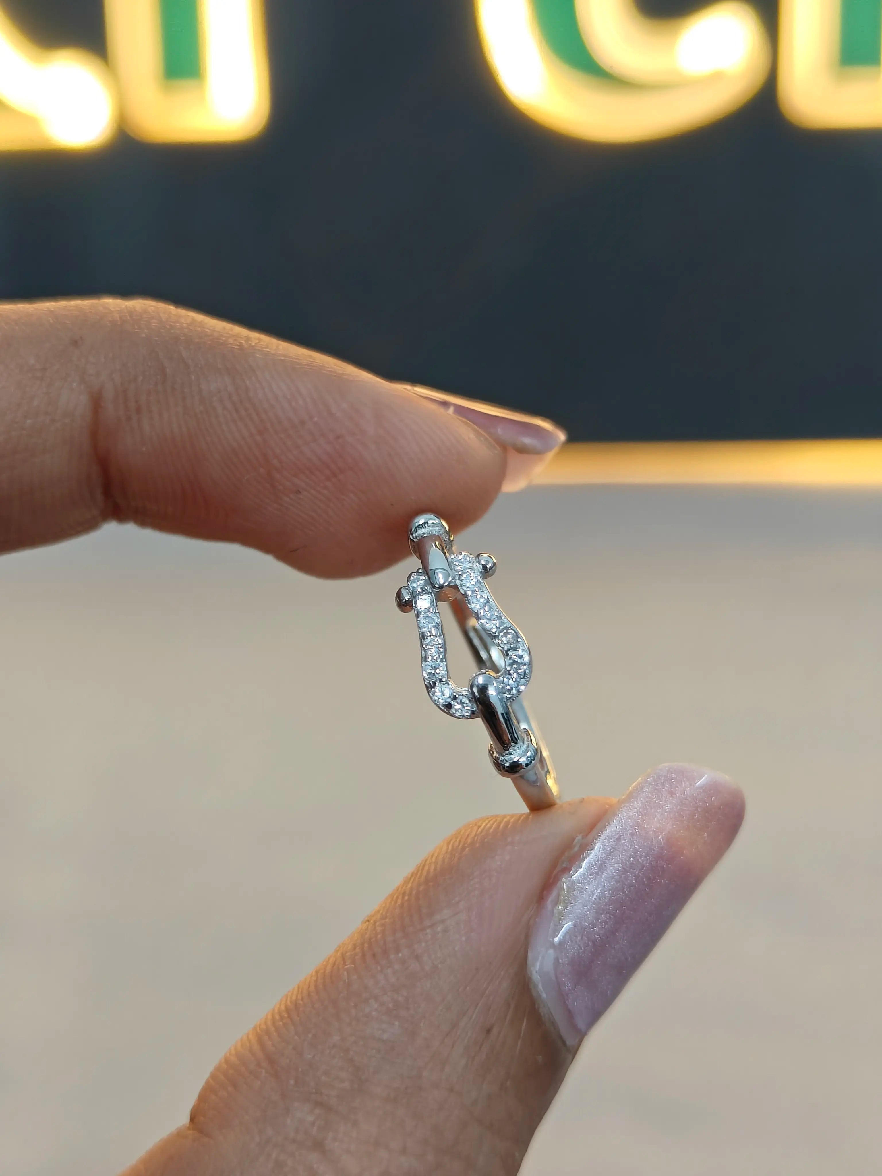 Silver ring with diamonds held between fingers against a blurred background