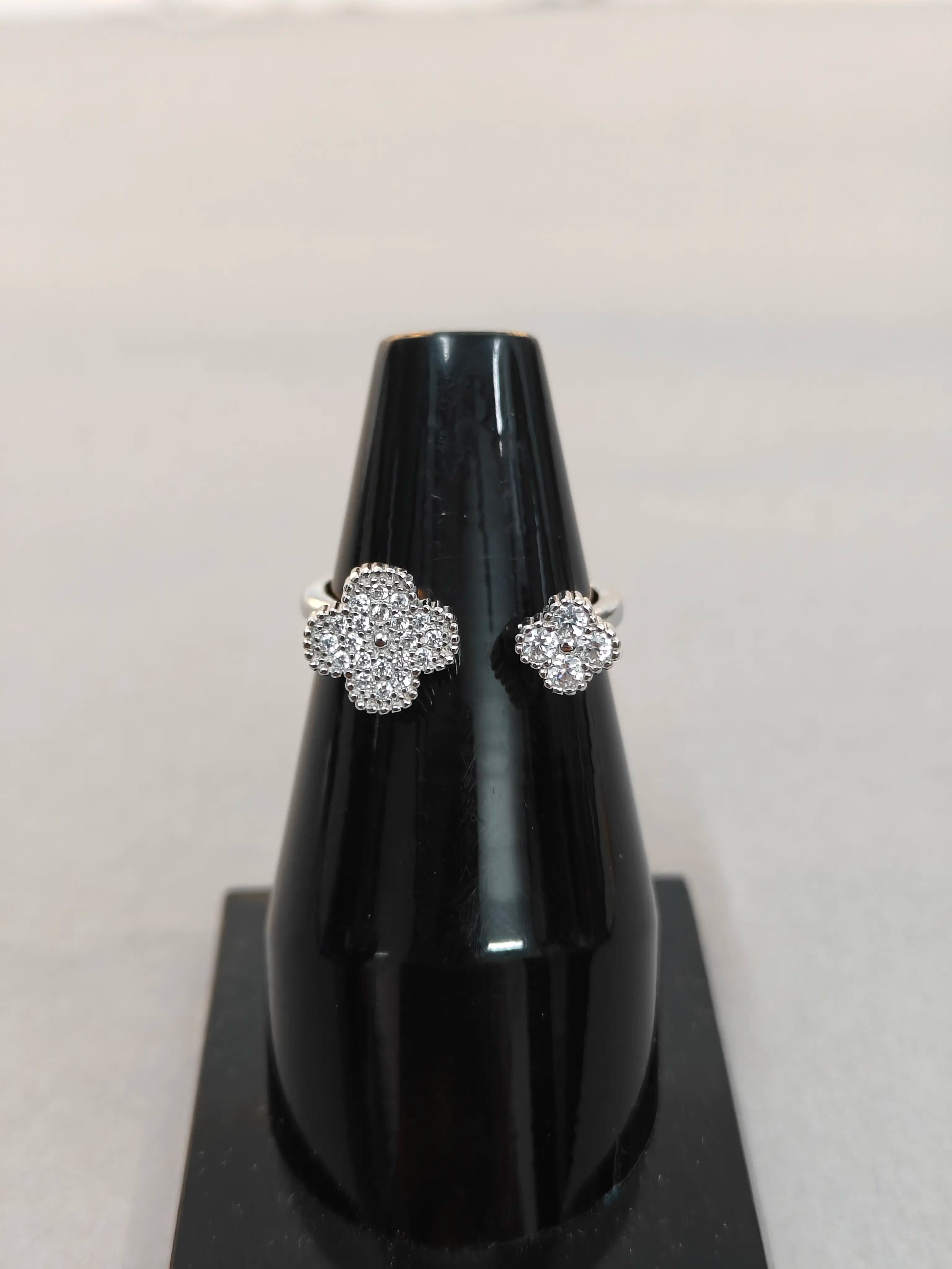 Pair of silver earrings on a black stand against a light gray background