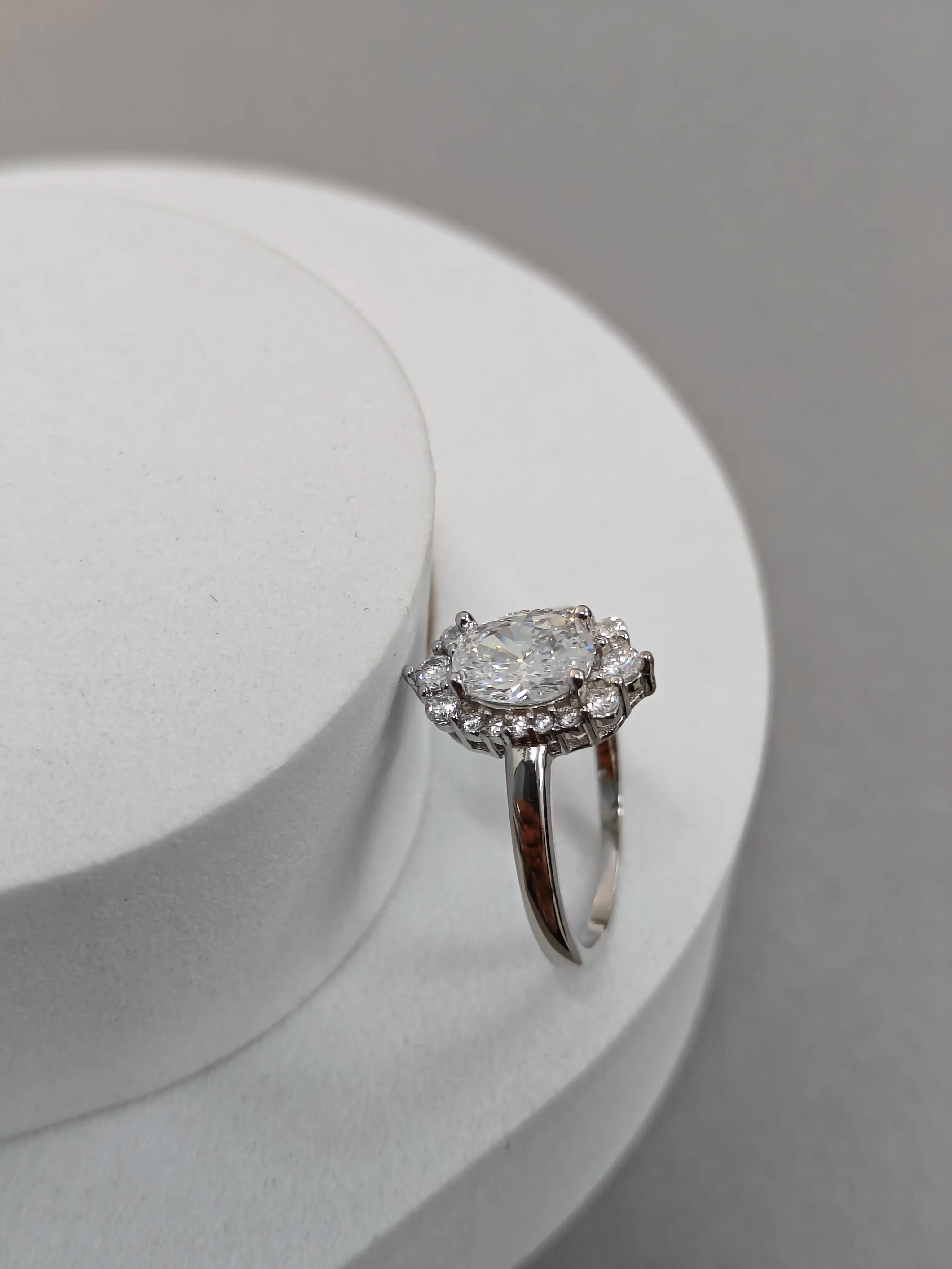 Diamond ring on a white stand with a gray background