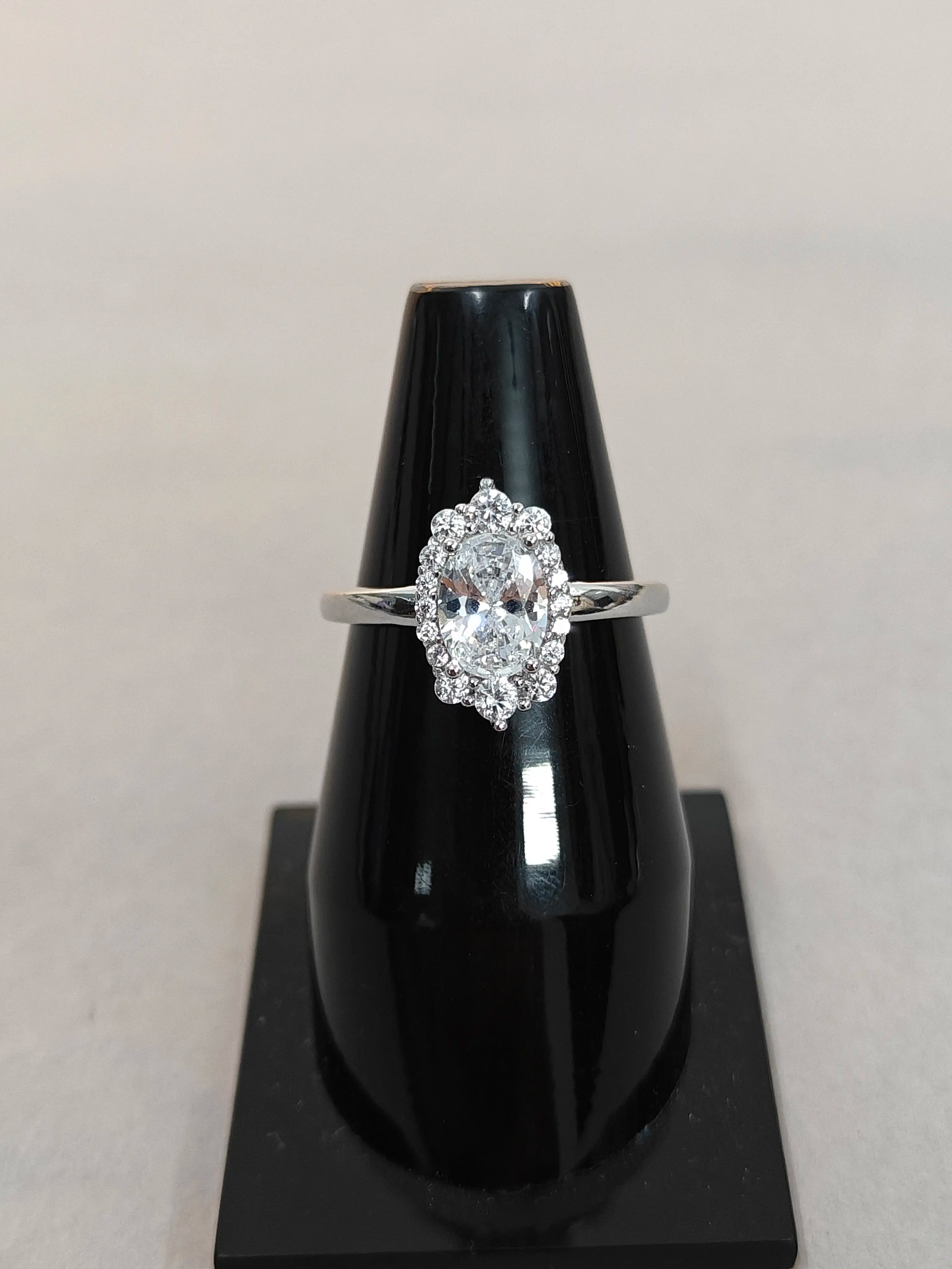 Diamond ring on a black stand against a light gray background