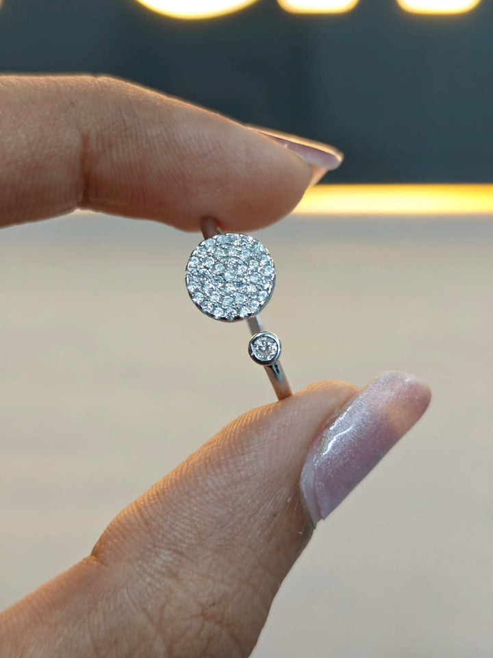 Close-up of a hand holding a diamond earring with a blurred background