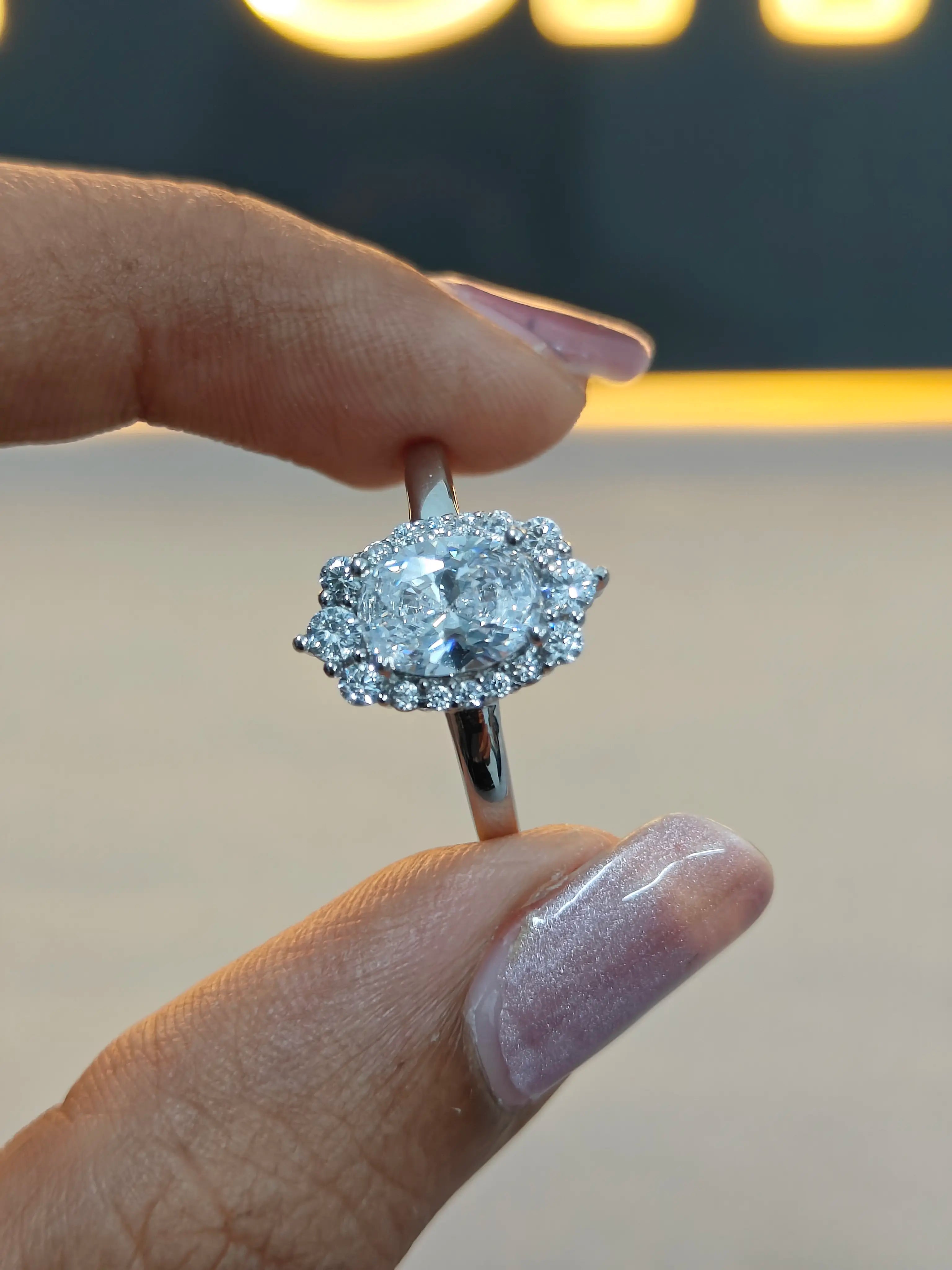 Diamond ring held between fingers with a blurred background