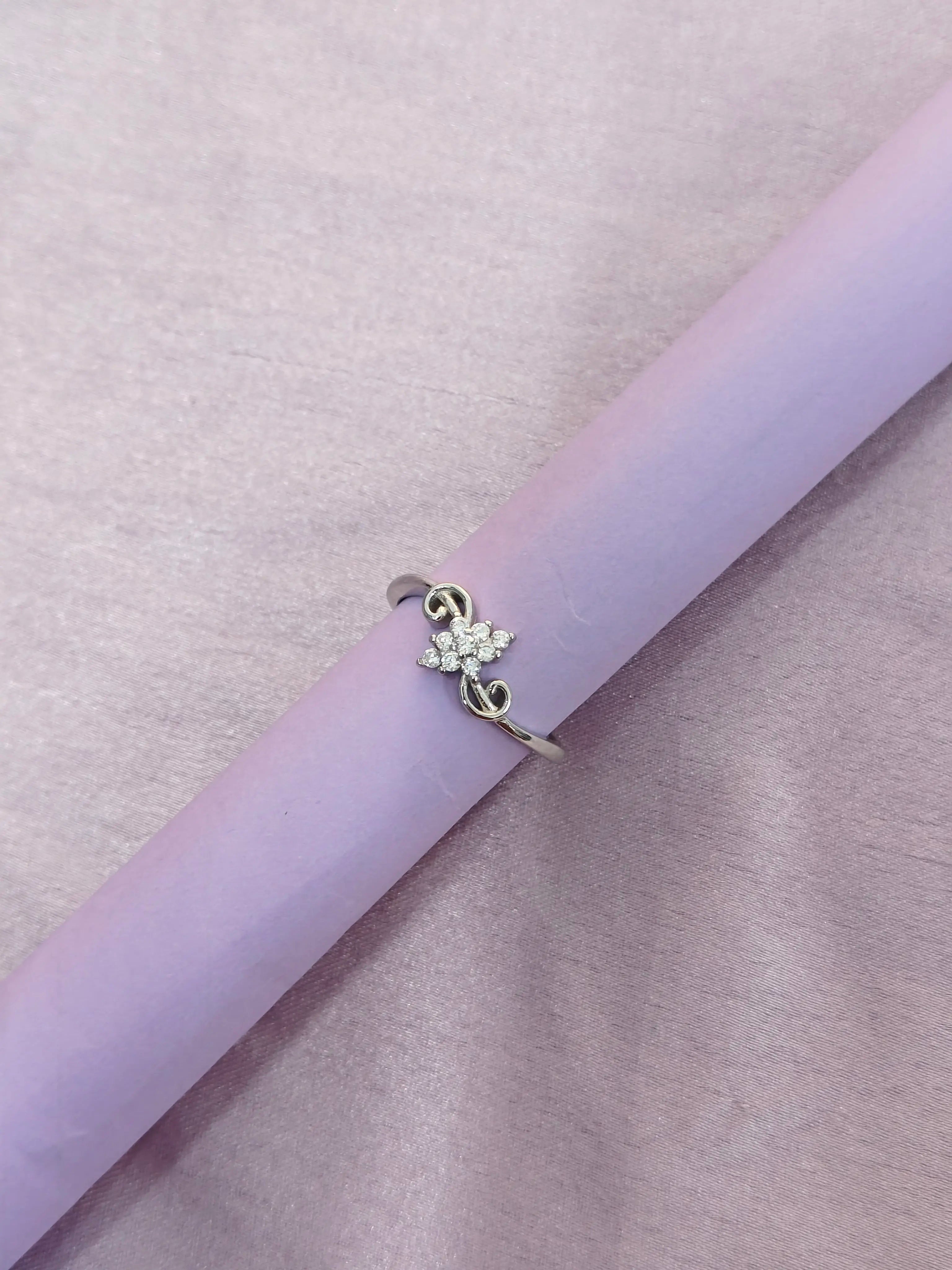 Silver ring with a floral design on a light purple surface