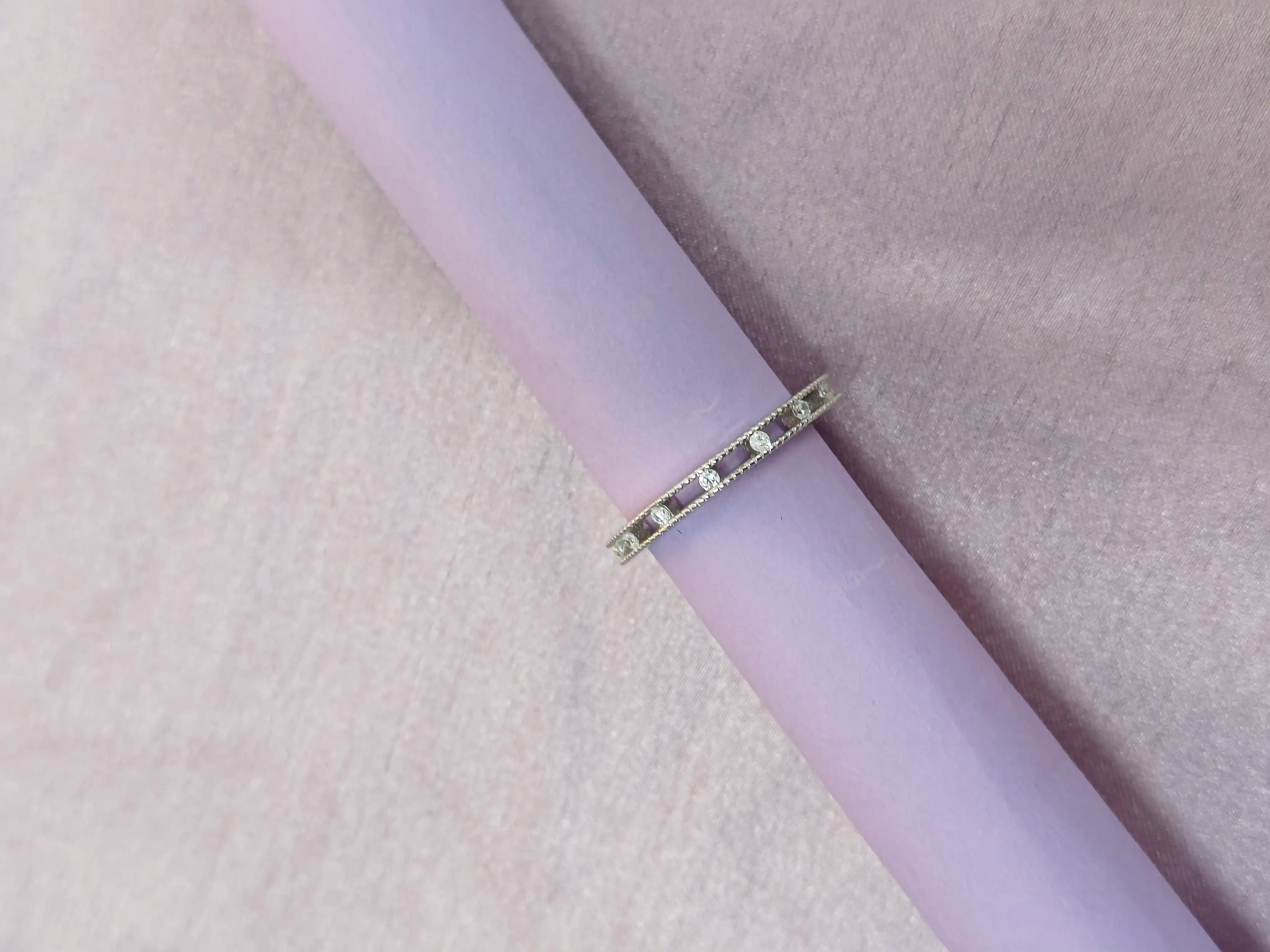 Gold ring on a pink cylindrical object against a pink background