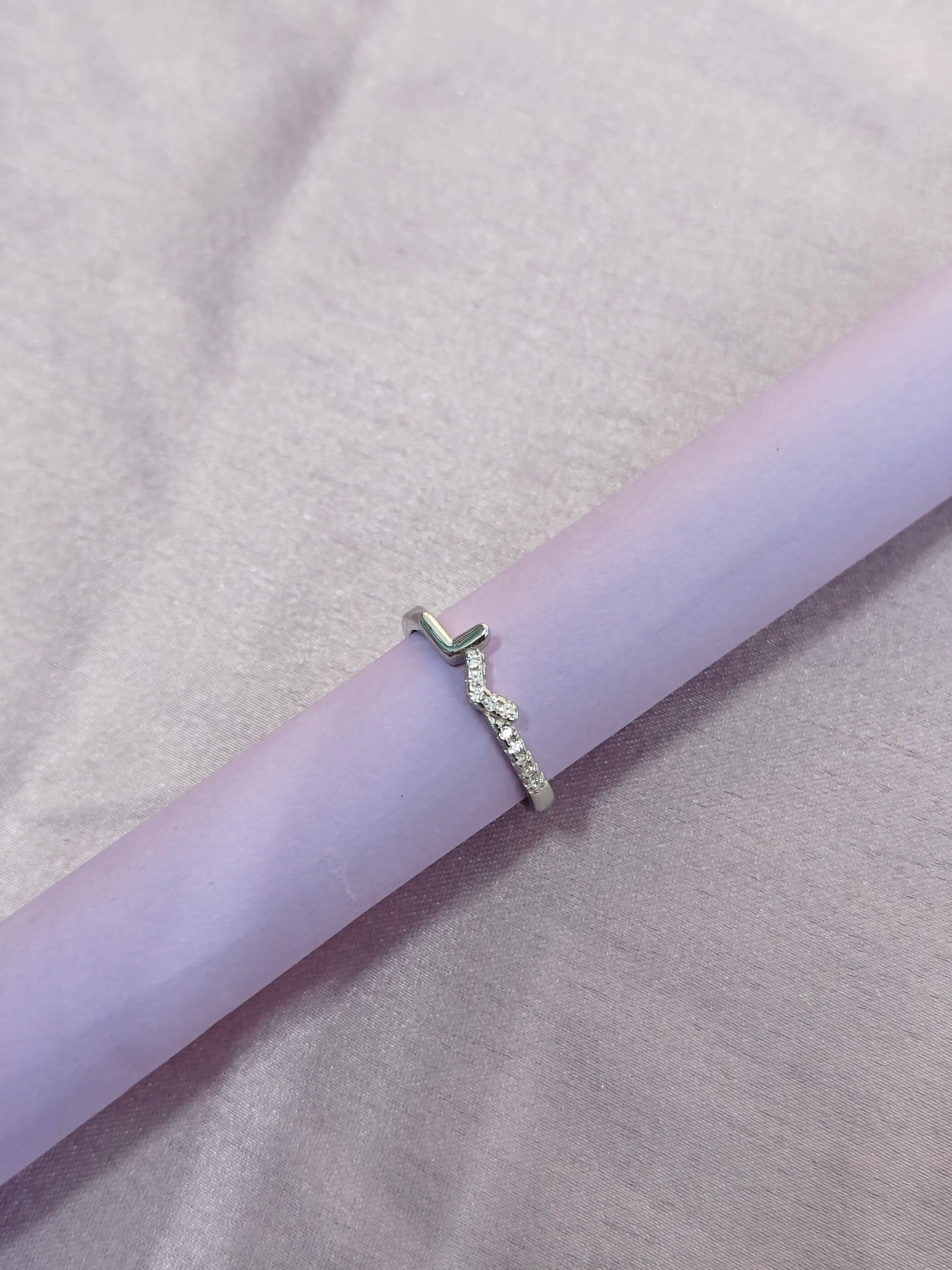 Silver ring on a light purple cylindrical object with a soft pink background