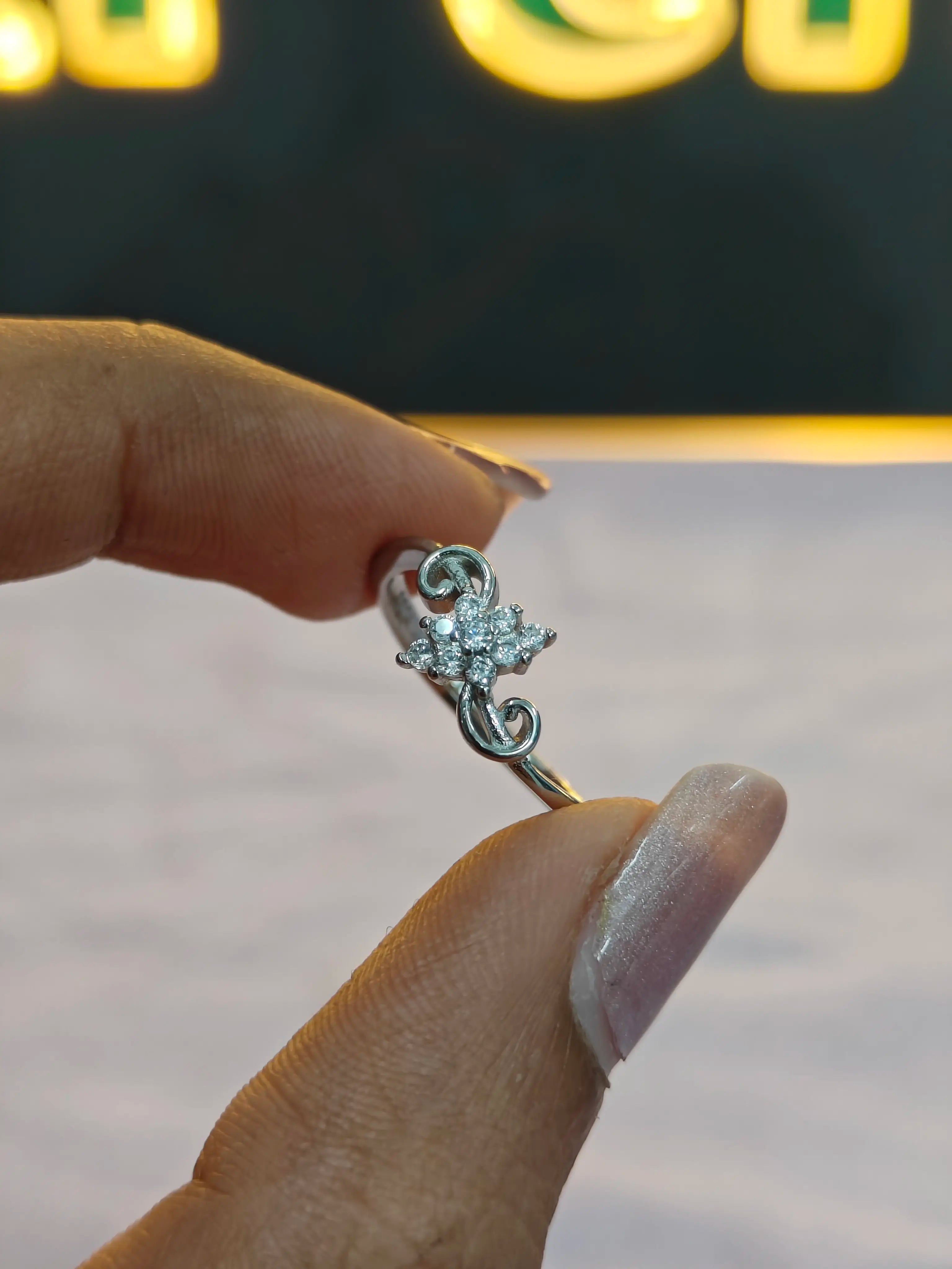 Silver earring held between fingers with a blurred background
