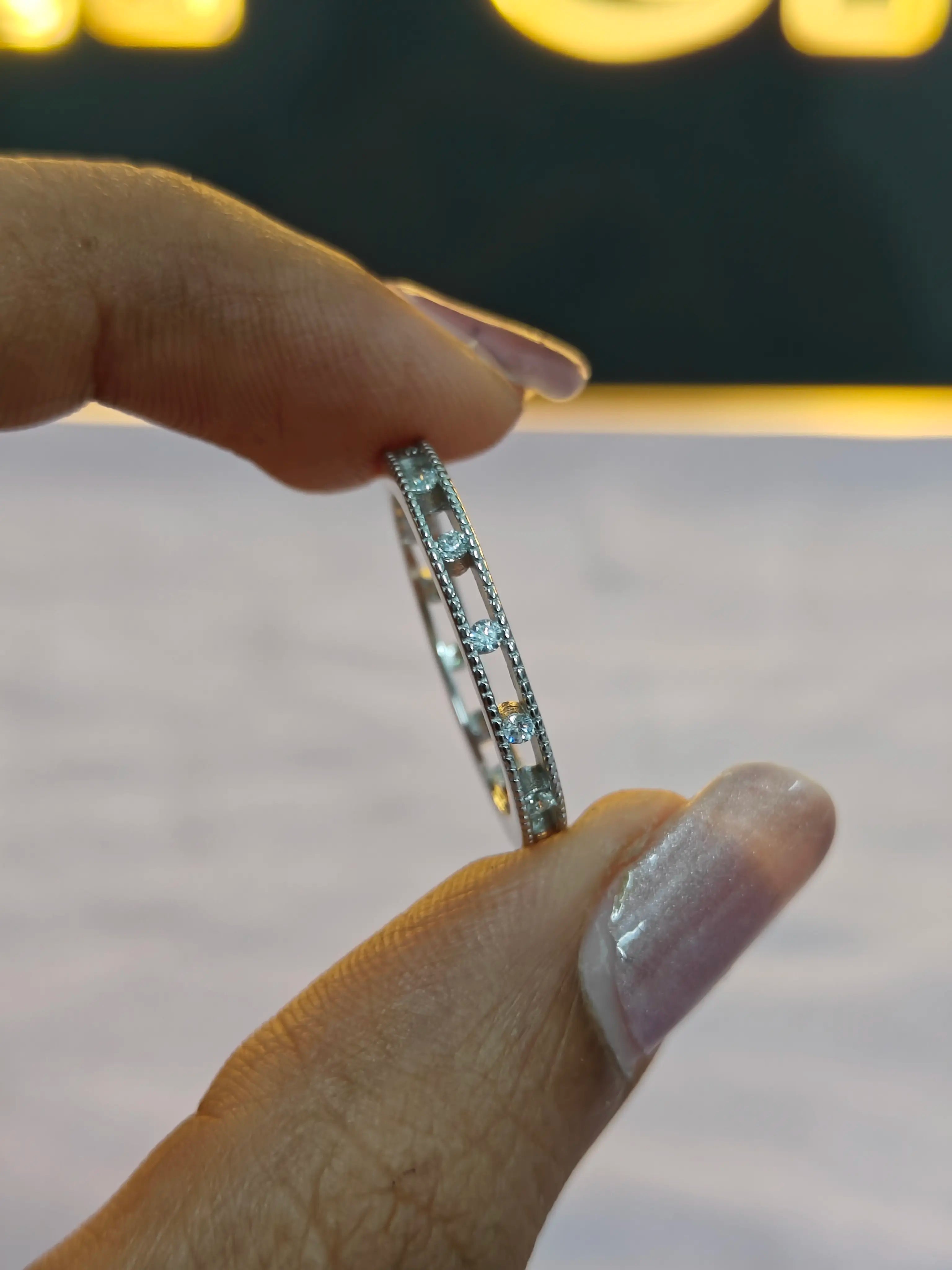 Silver ring with blue gemstones held by a hand against a blurred background