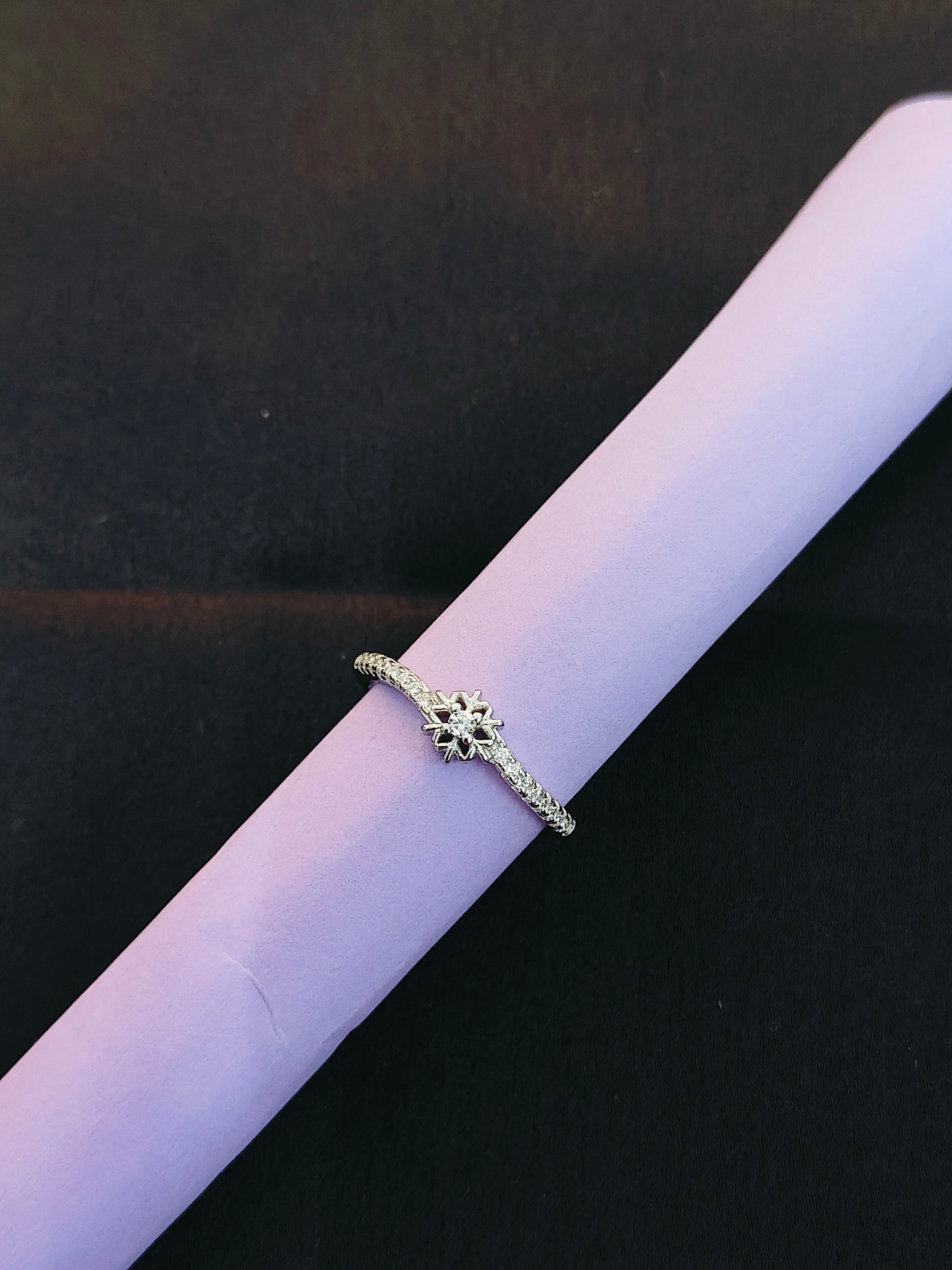 Silver ring with small diamonds on a black background