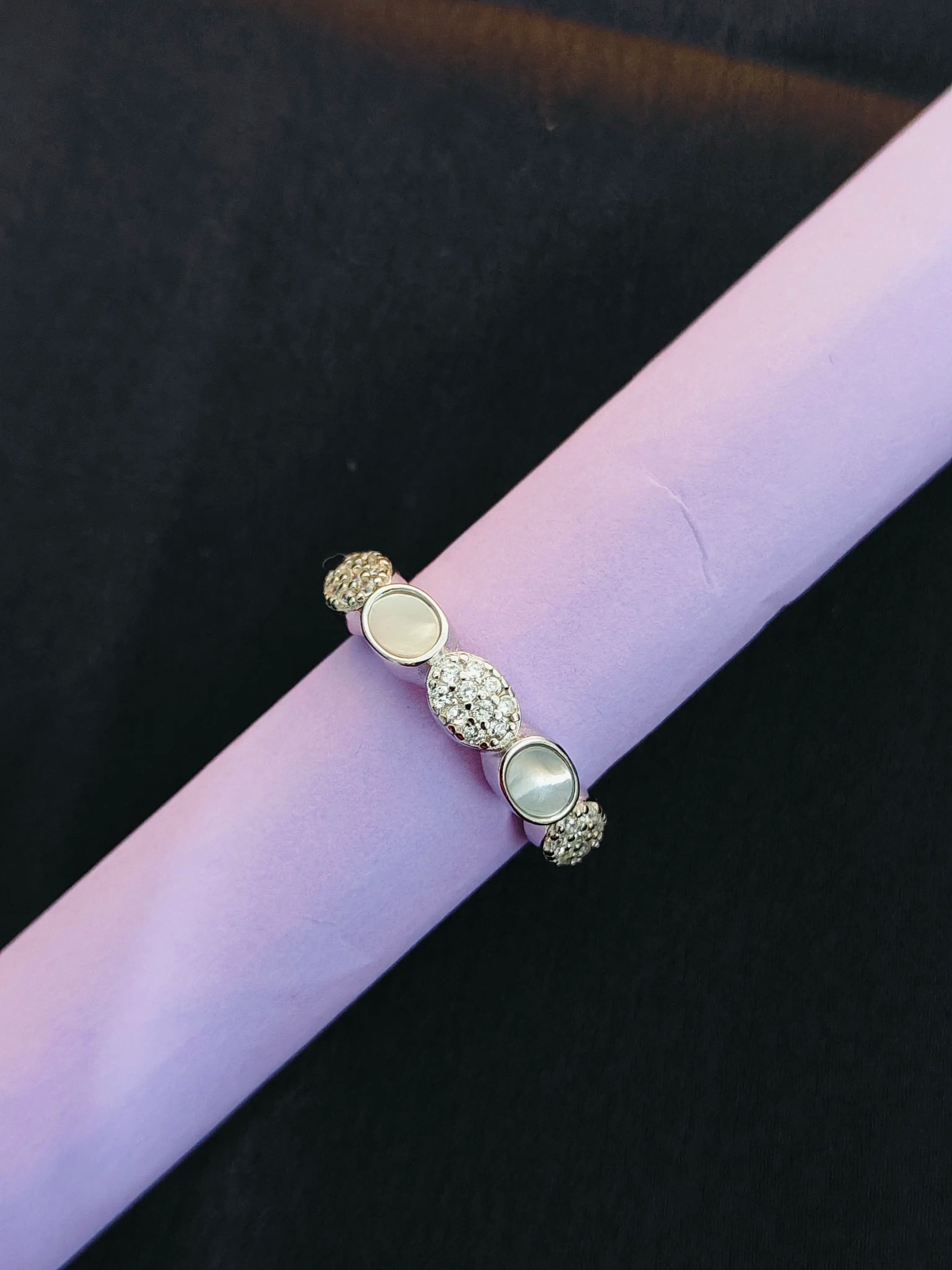 Silver ring with circular stones on a purple surface