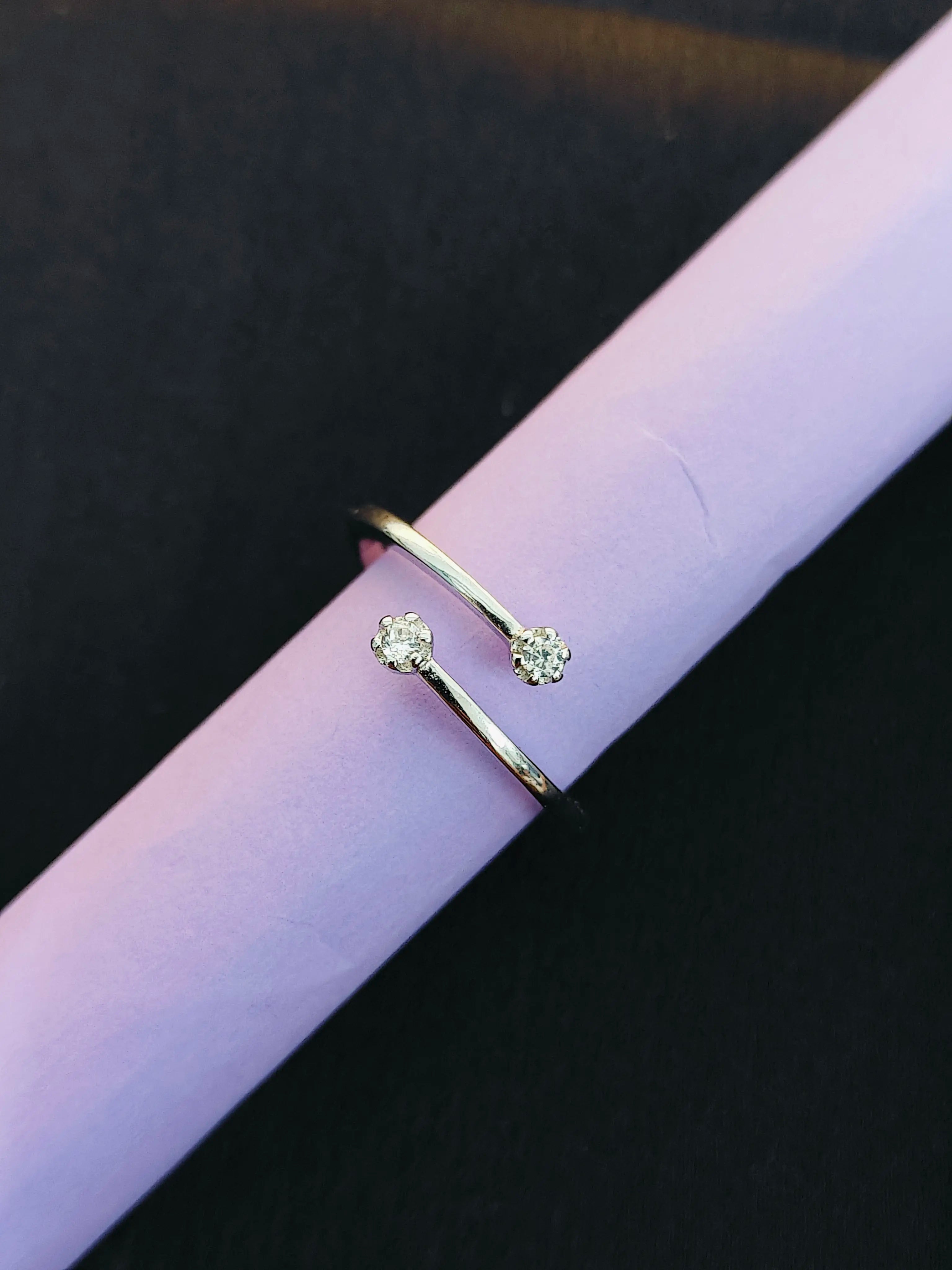 Gold ring with a small diamond on a pink surface