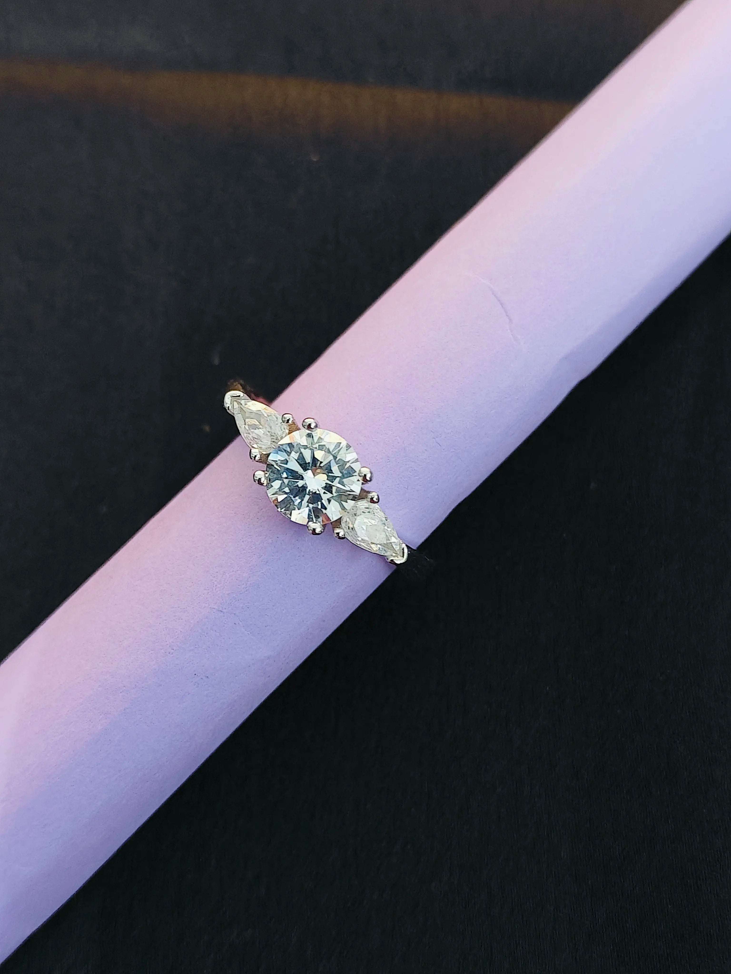 Diamond ring on a purple cushion against a dark background