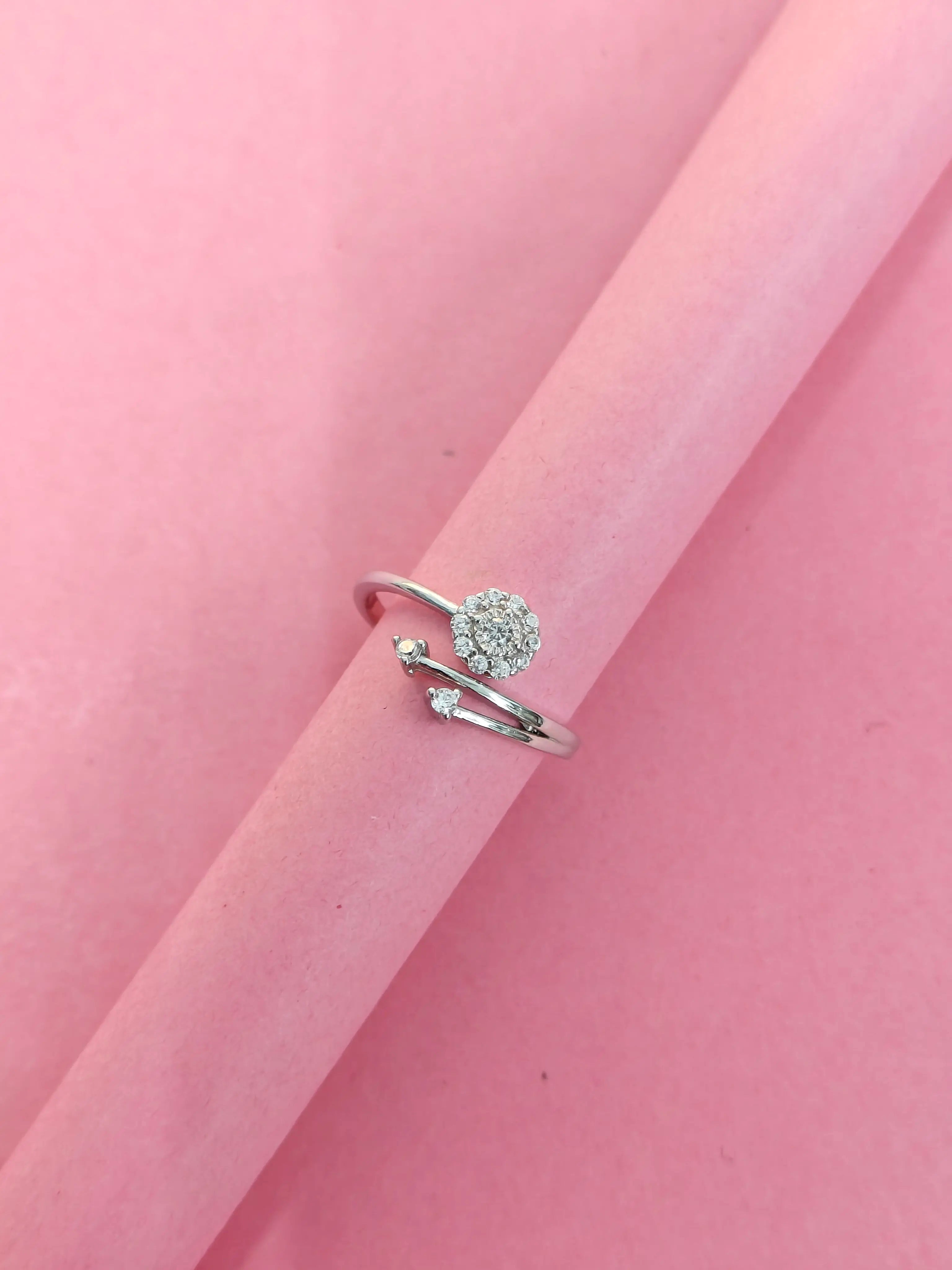 Silver ring with a heart-shaped design on a pink background