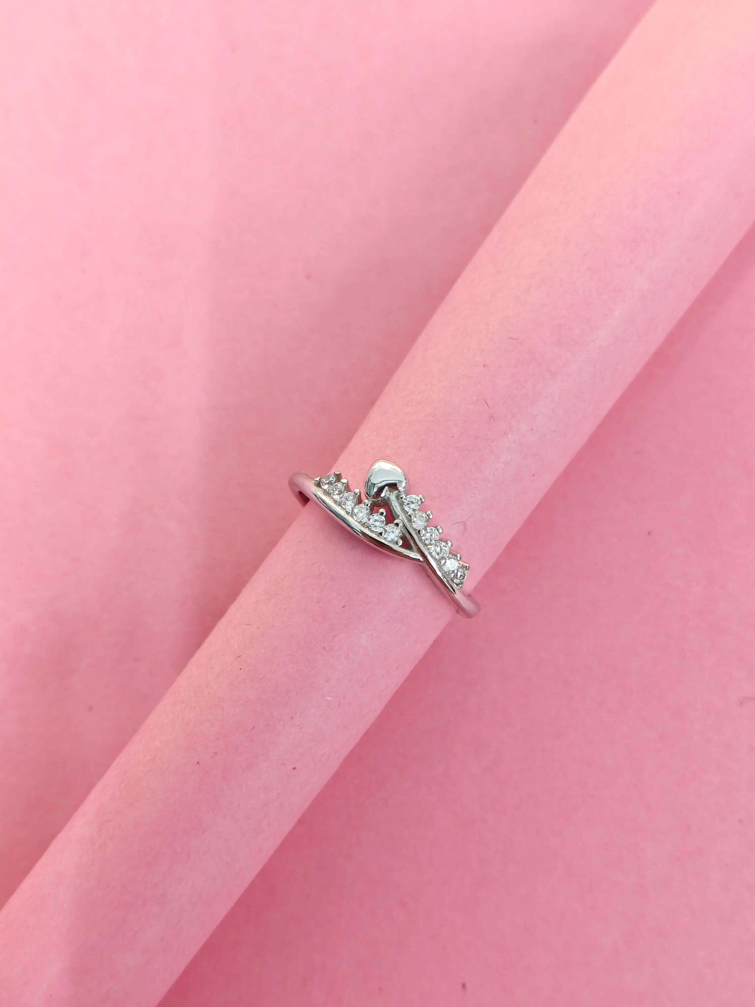 Silver ring with small diamonds on a pink fabric background