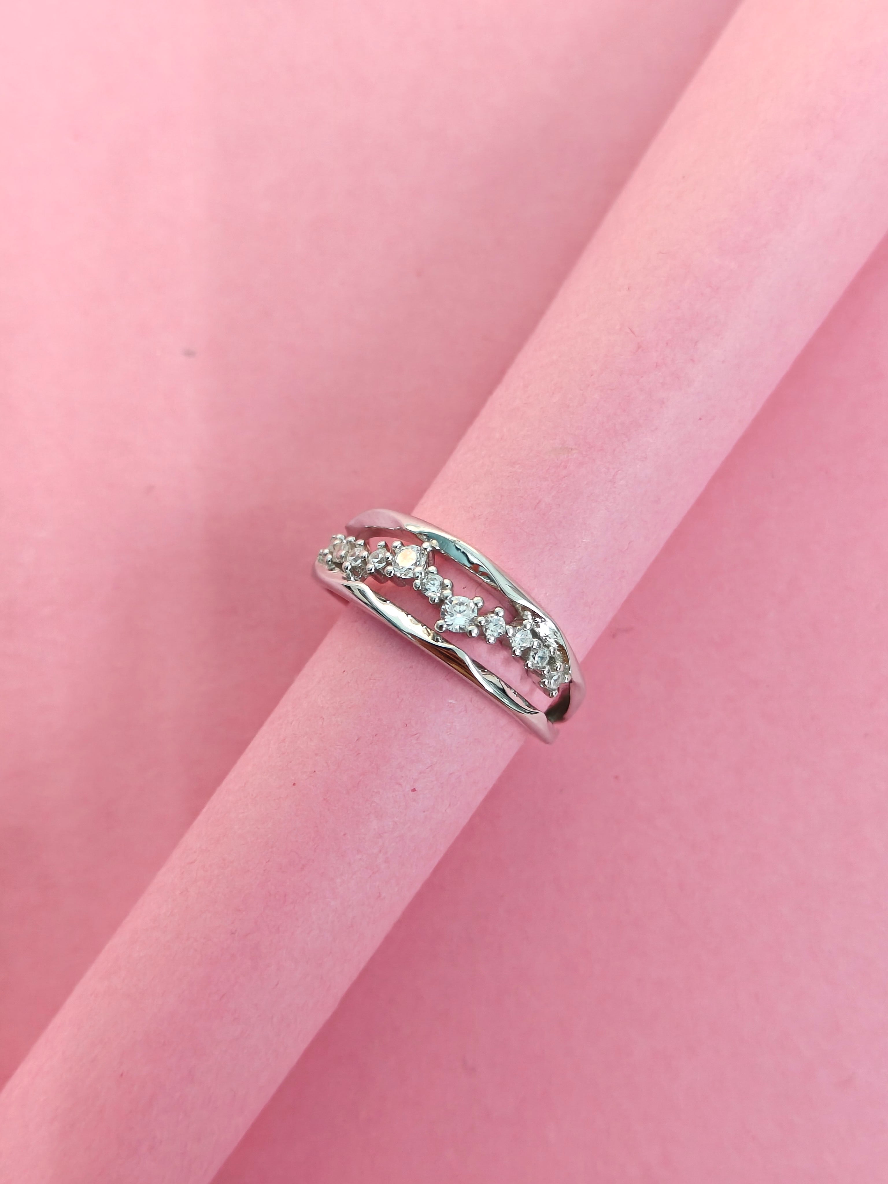 Silver ring with small diamonds on a pink fabric background