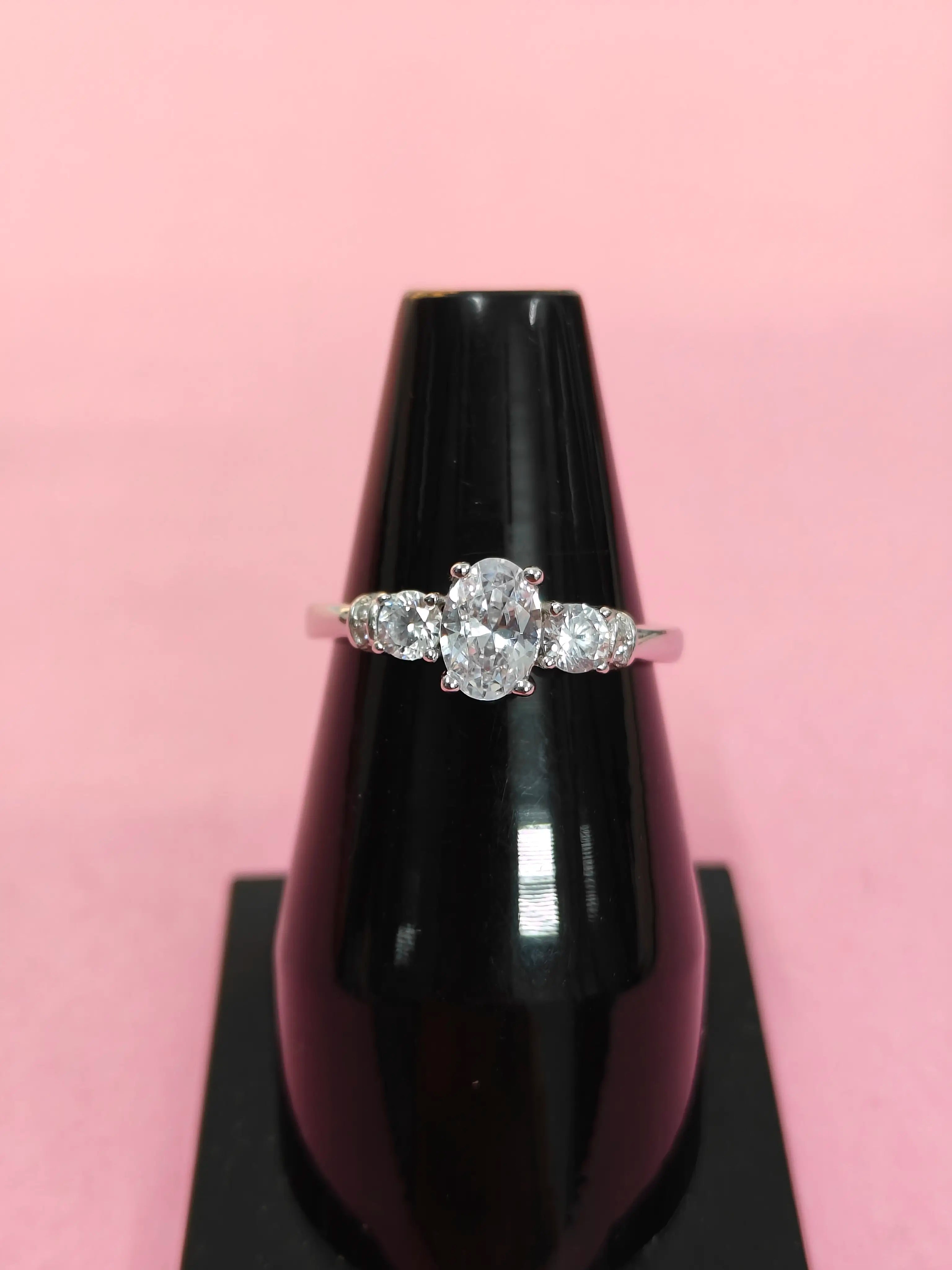 Diamond ring on a black stand with a pink background