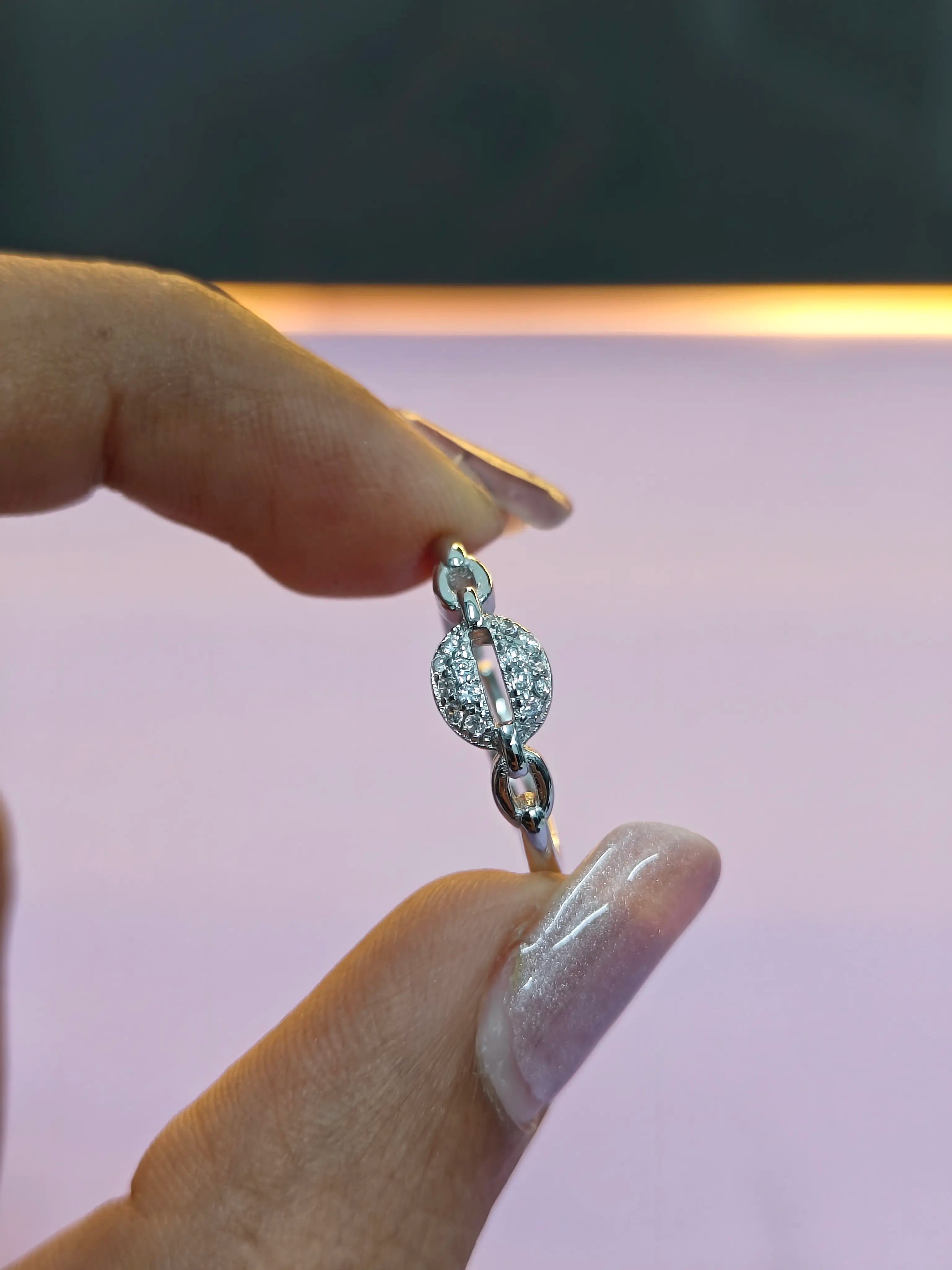 Silver bracelet with a diamond clasp held by a hand against a blurred background