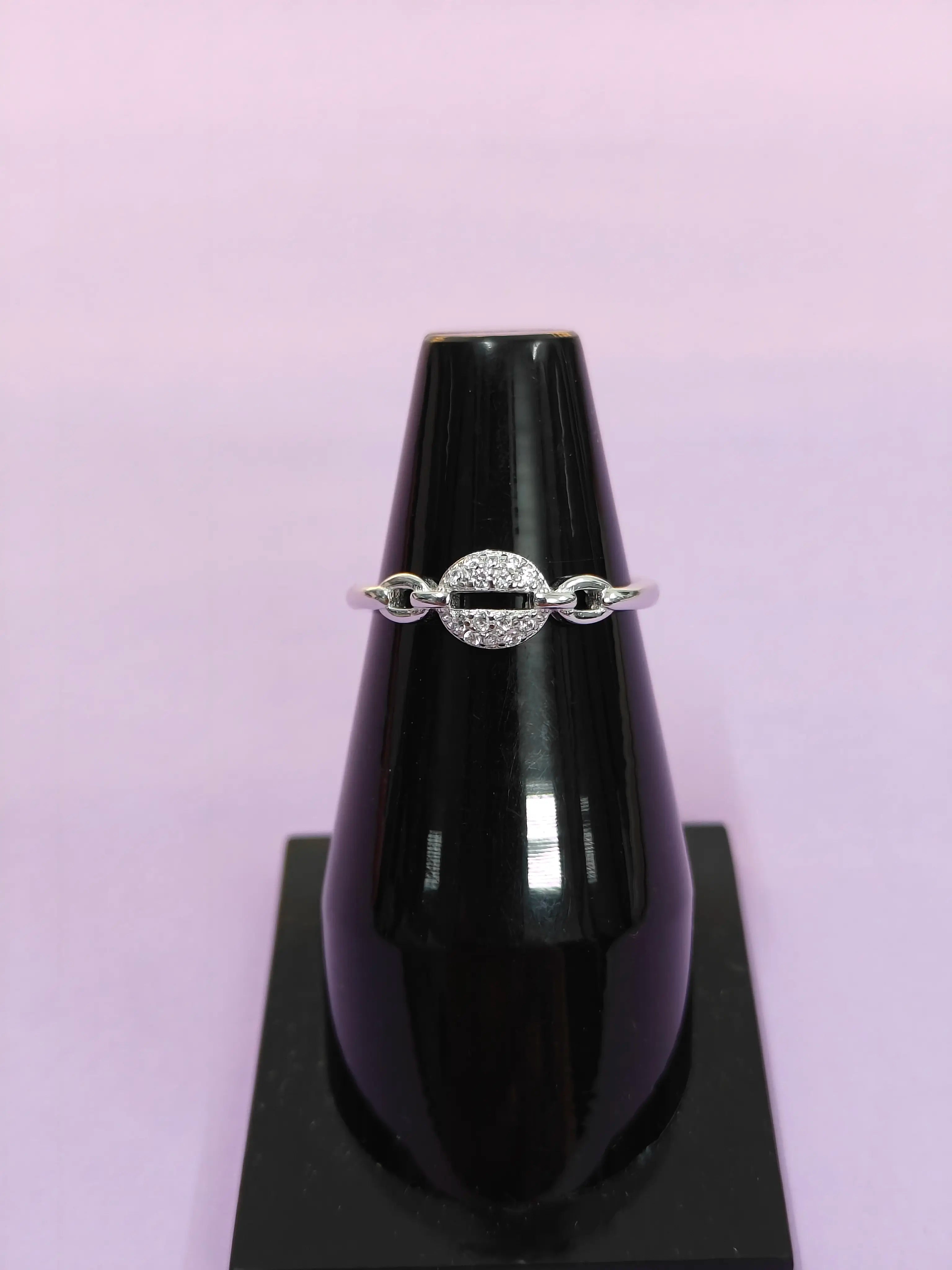 Silver ring on a black jewelry display with a purple background