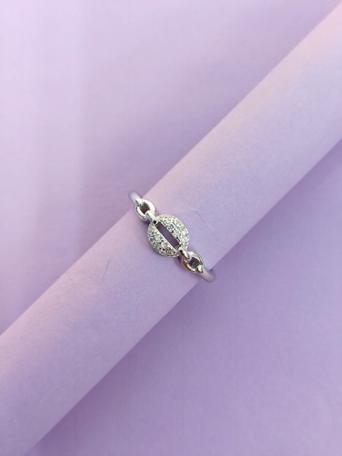 Silver ring with a circular design on a light purple background
