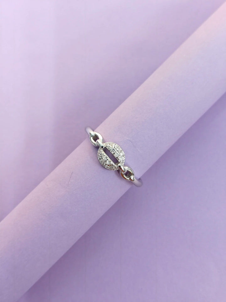 Silver ring with a circular design on a light purple background