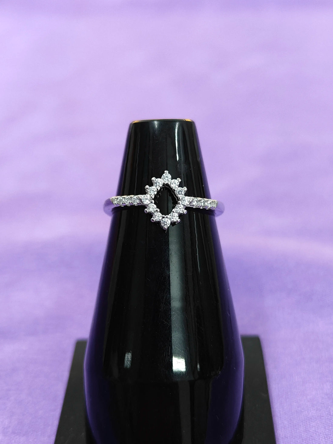 Diamond ring on a black stand with a purple background