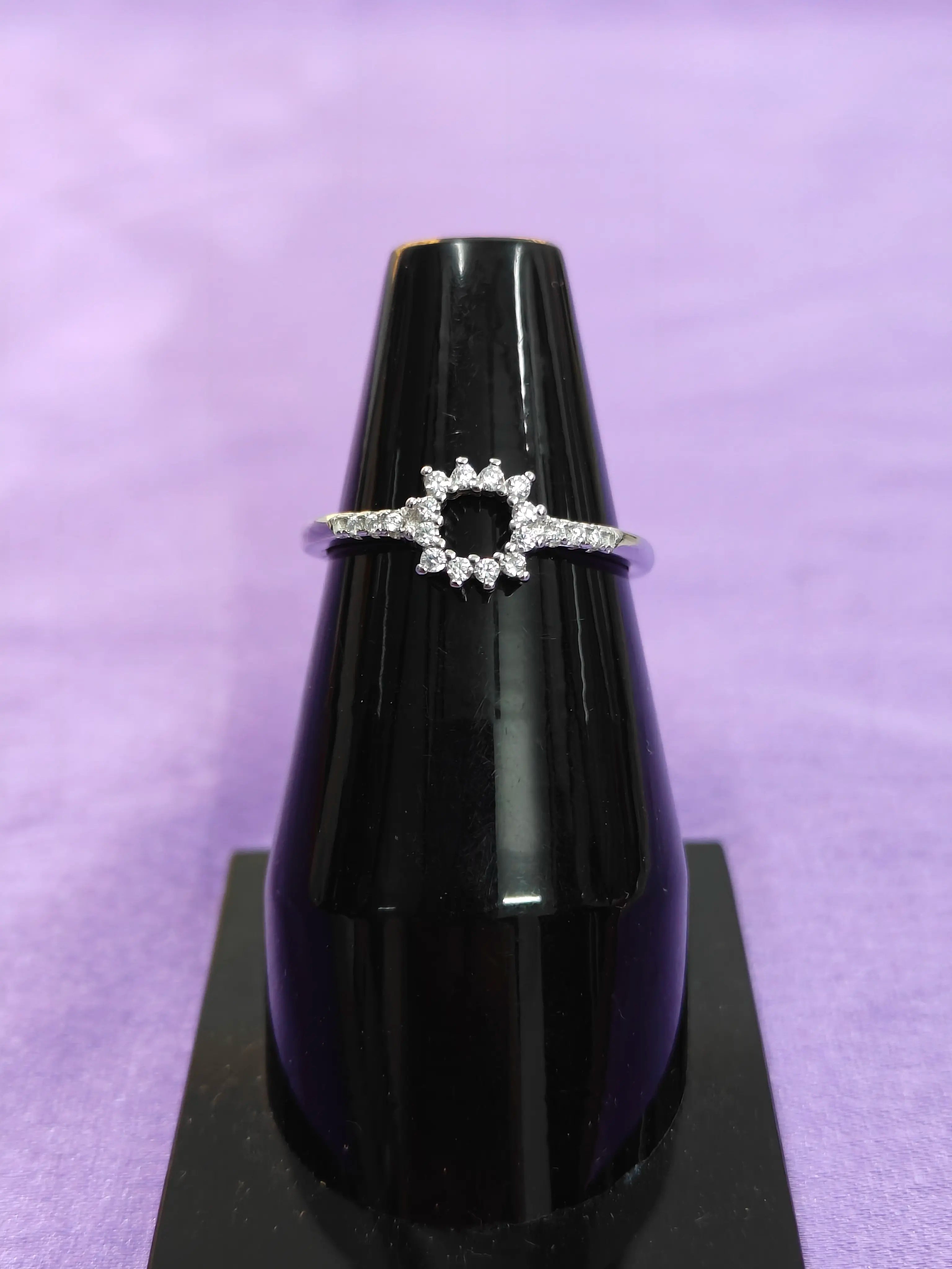 Diamond ring on a black stand against a purple background
