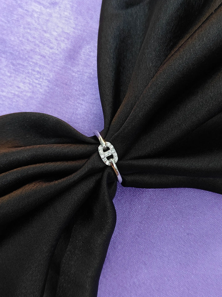 Black fabric with a silver ring featuring a diamond on a purple background