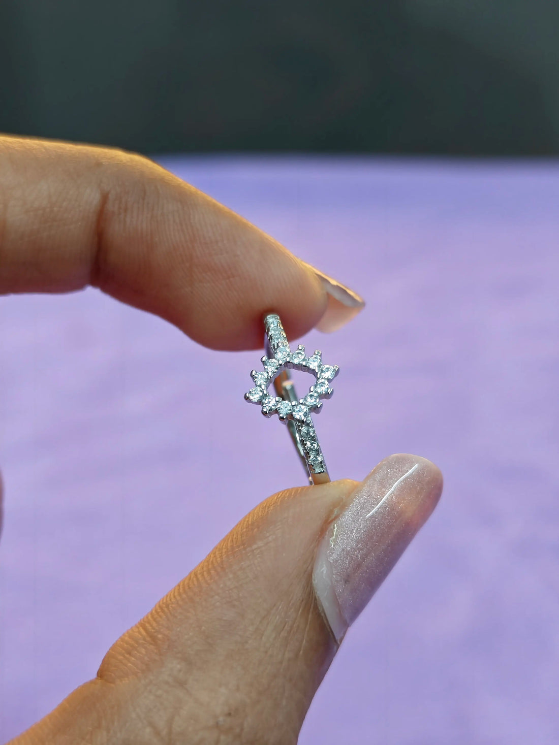 Silver ring with a star design held by a hand against a blurred background