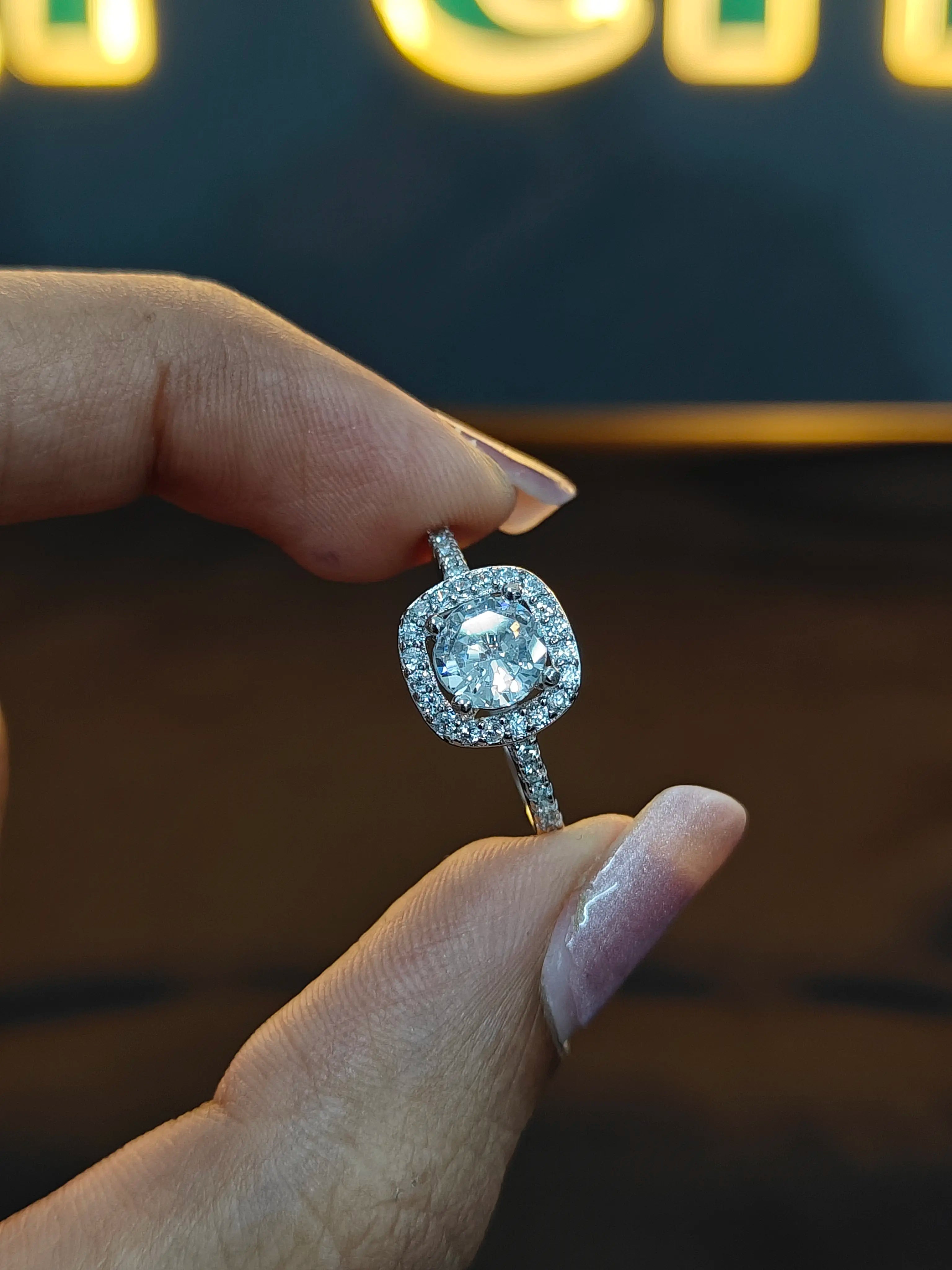 Diamond ring held between fingers with a blurred background