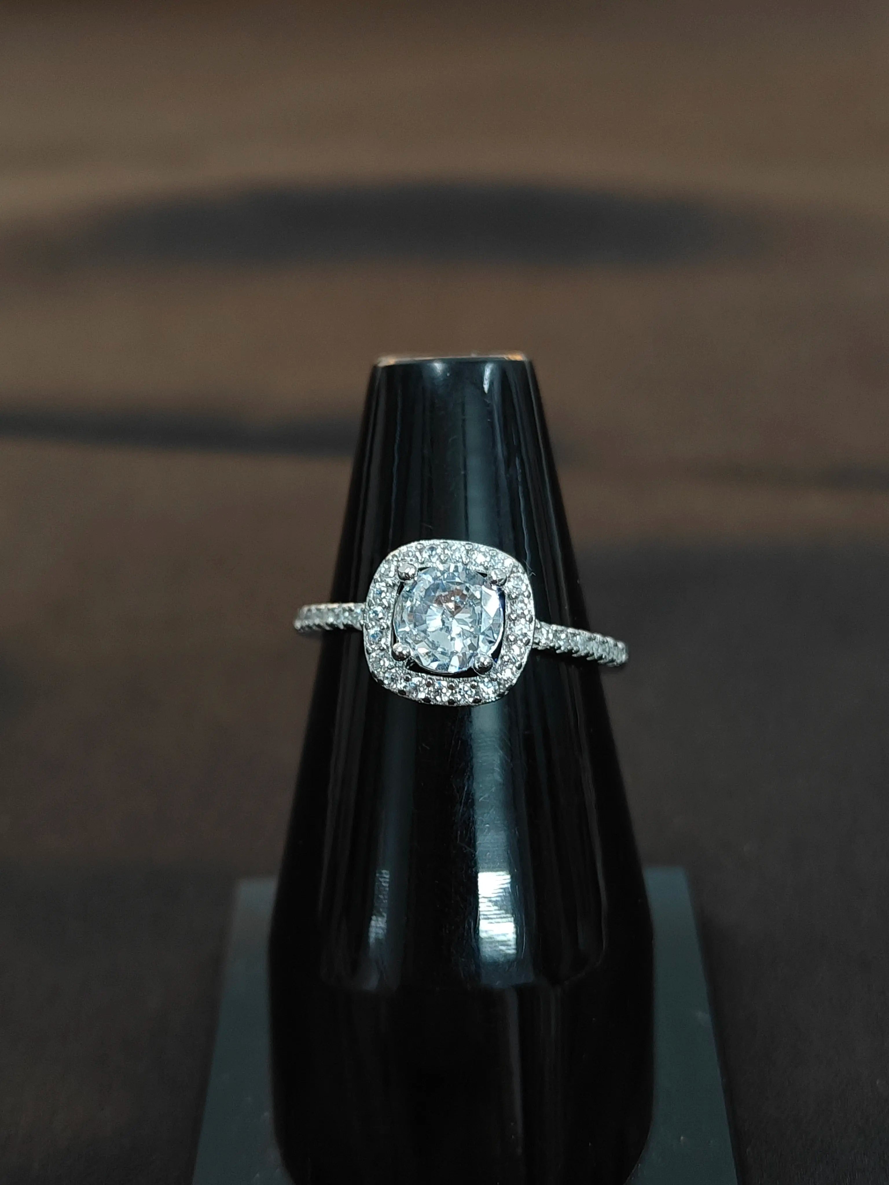 Diamond ring on a black stand against a dark background