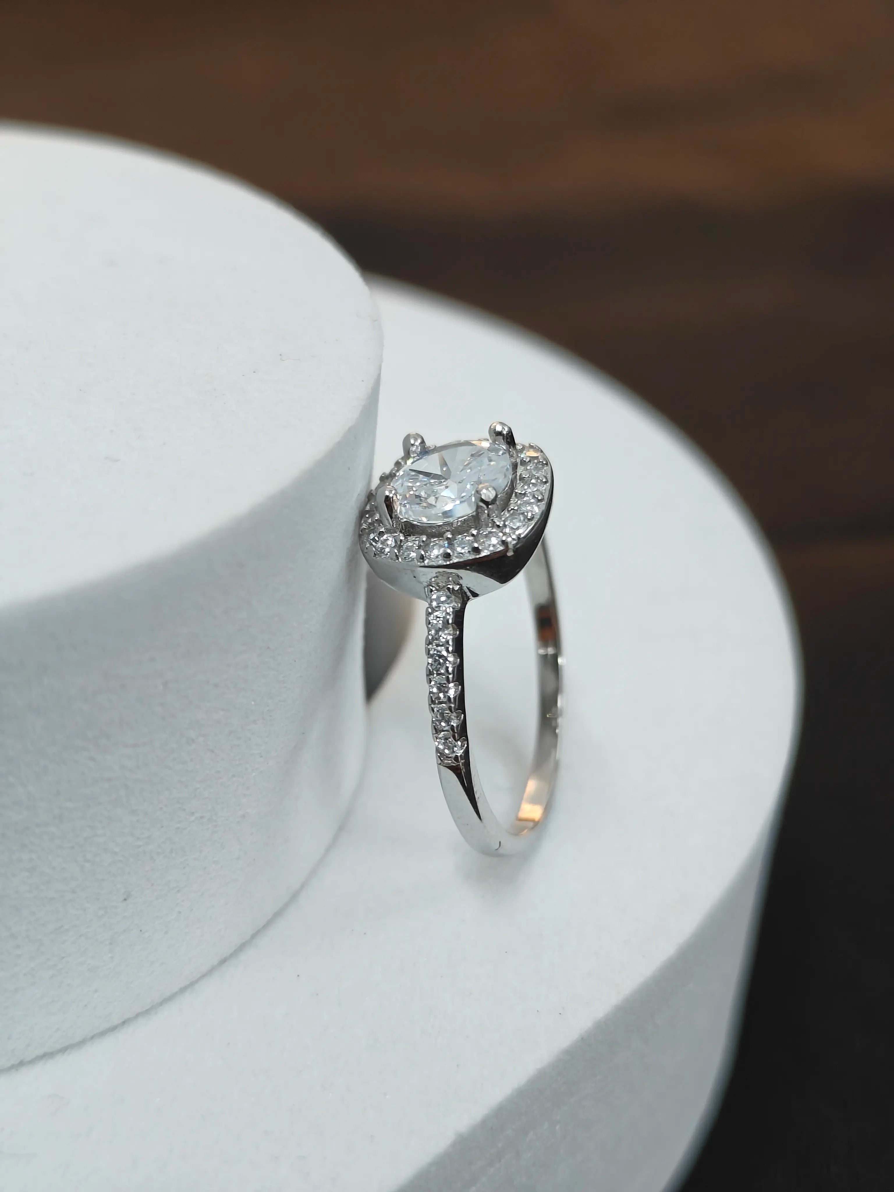 Silver ring with a diamond on a white stand