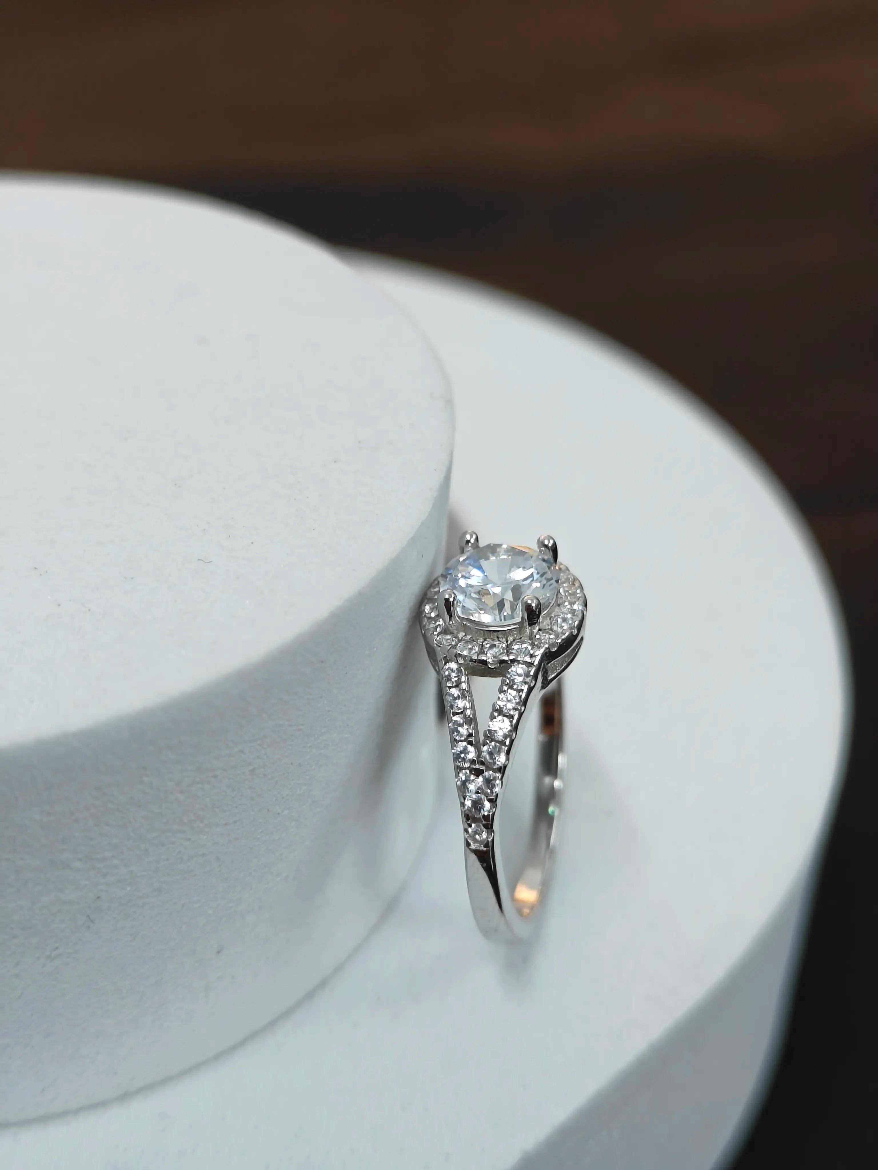 Silver ring with a diamond on a white stand