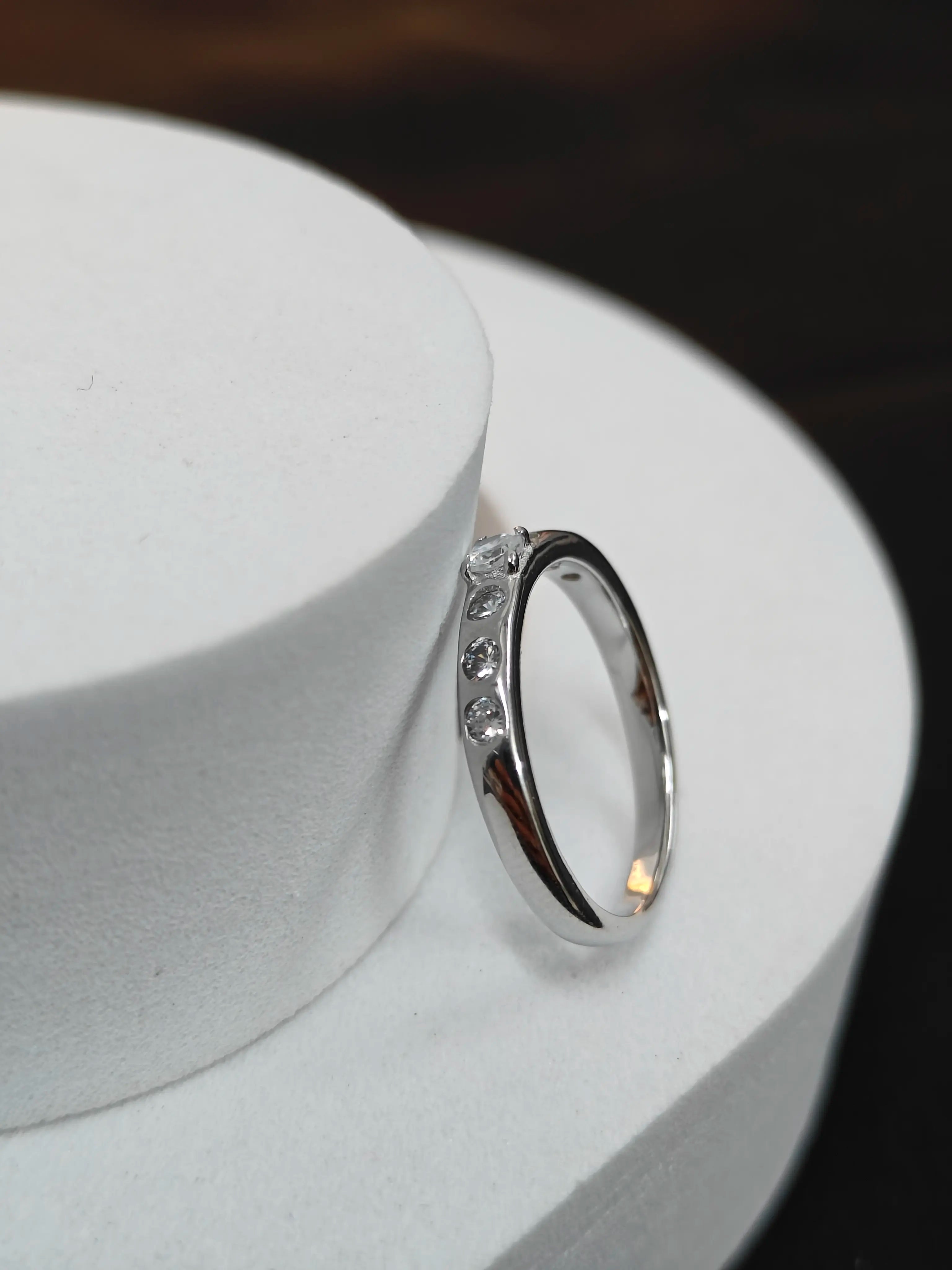 Silver ring with small diamonds on a white stand